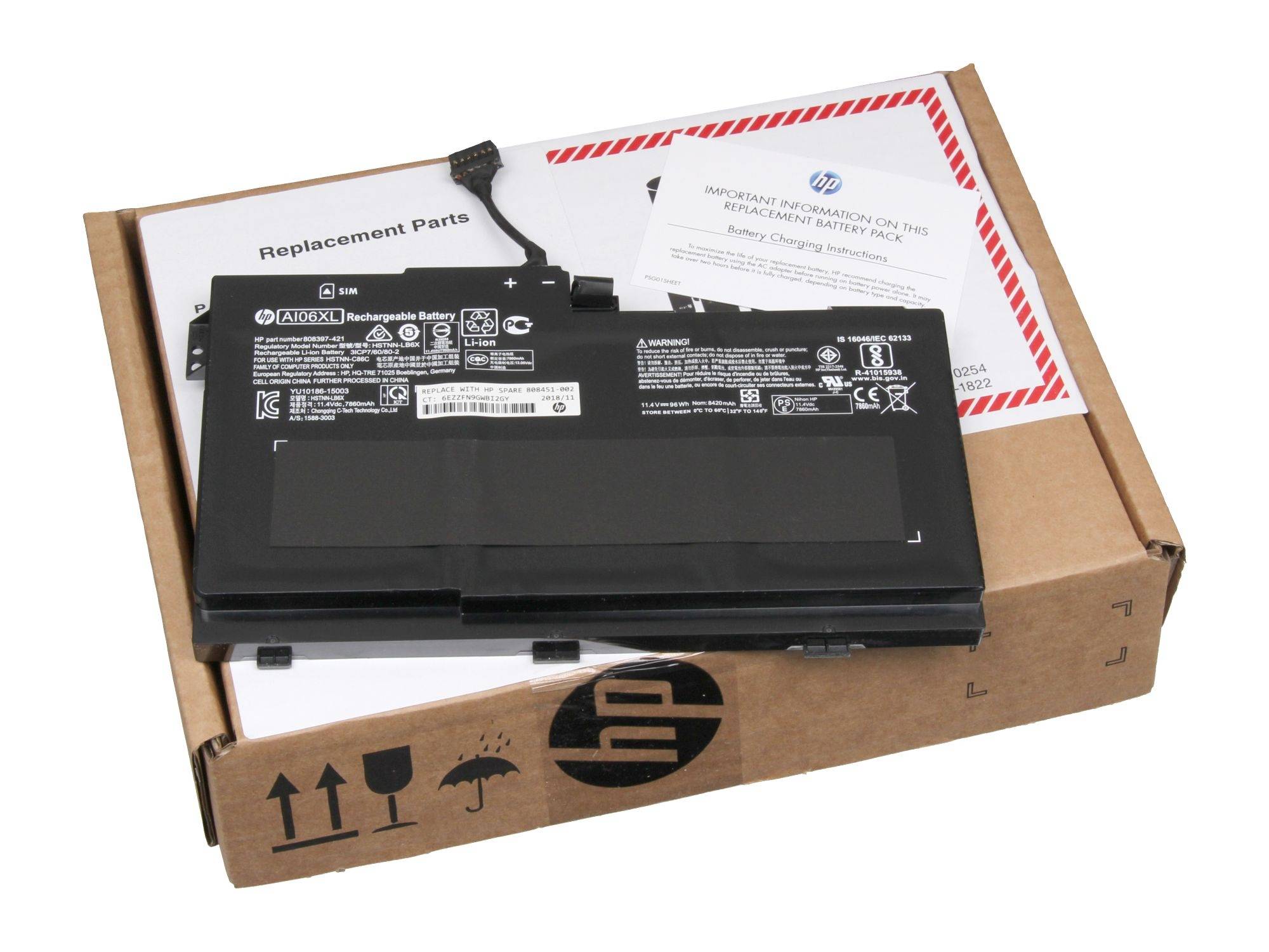 Baterie notebooku HP leží na kartonu s náhradními díly. Vedle ní je návod k použití zobrazující 'Battery Charger Information'.
