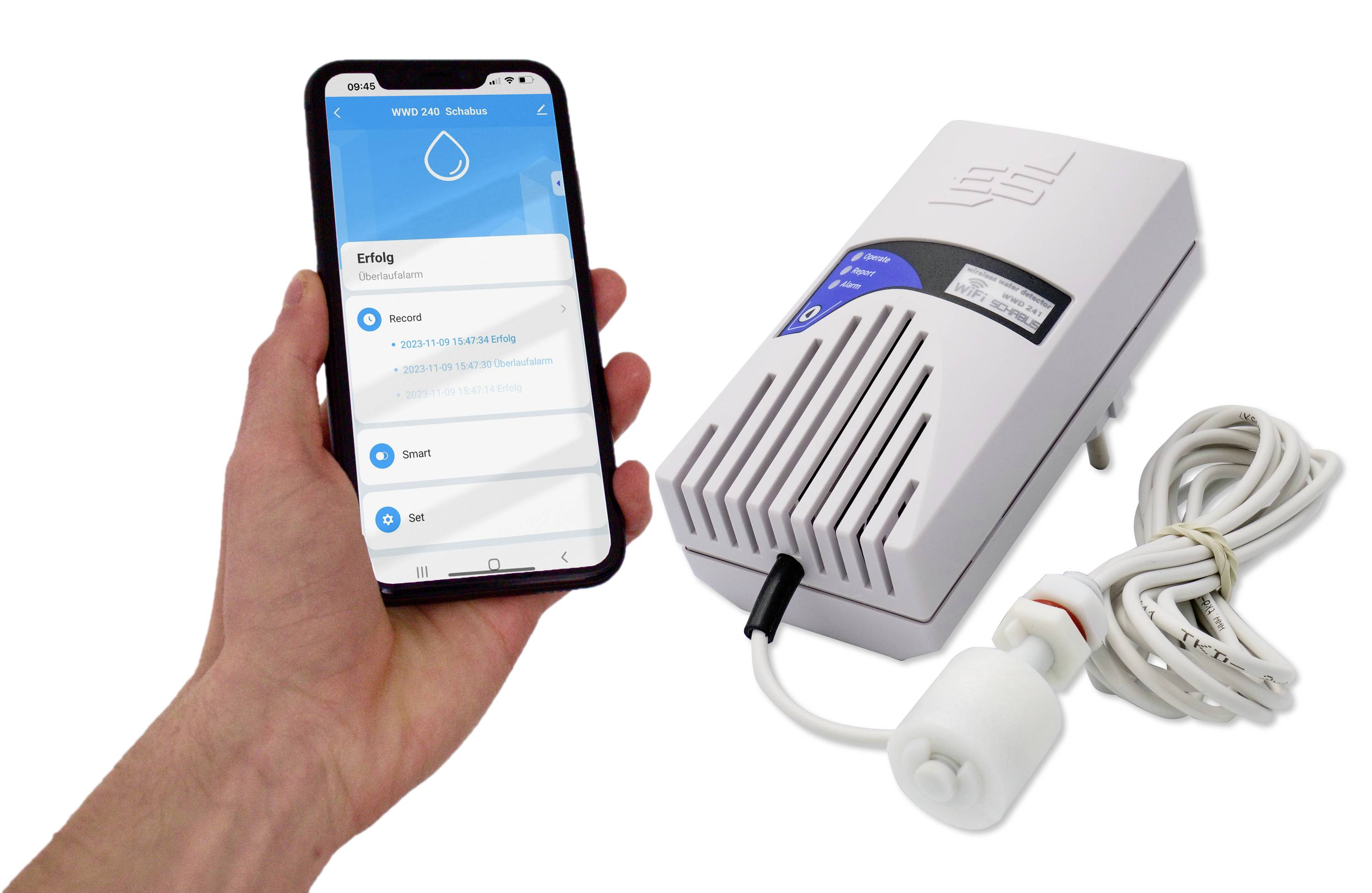 Ruka drží smartphone s aplikací zobrazující informace. Vedle něj leží bílé elektronické zařízení s kabelem.