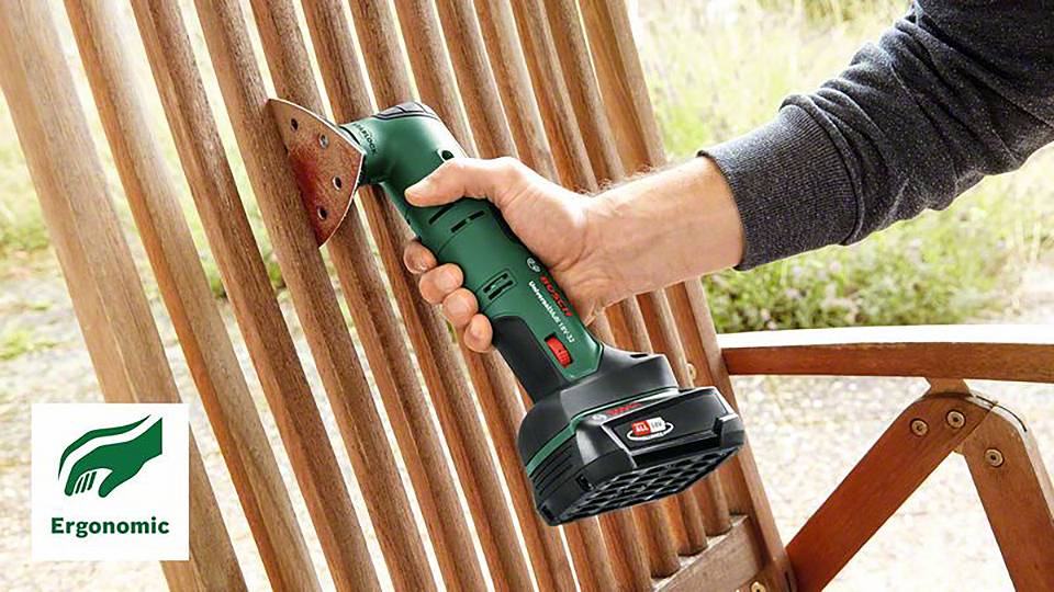 Osoba brousí dřevěnou židli bezdrátovým brusným zařízením. Důraz je kladen na ergonomický design. Logo zobrazuje nápis 'Ergonomic'.
