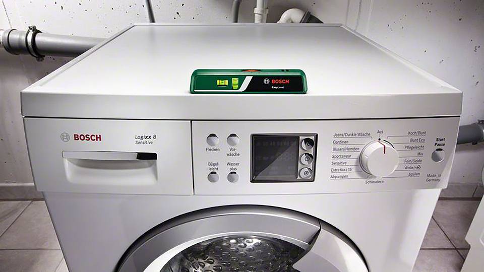 Pračka značky Bosch, model Logixx 8 Sensitive, v prádelně, zobrazující ovládací panel s různými programy a nastaveními.