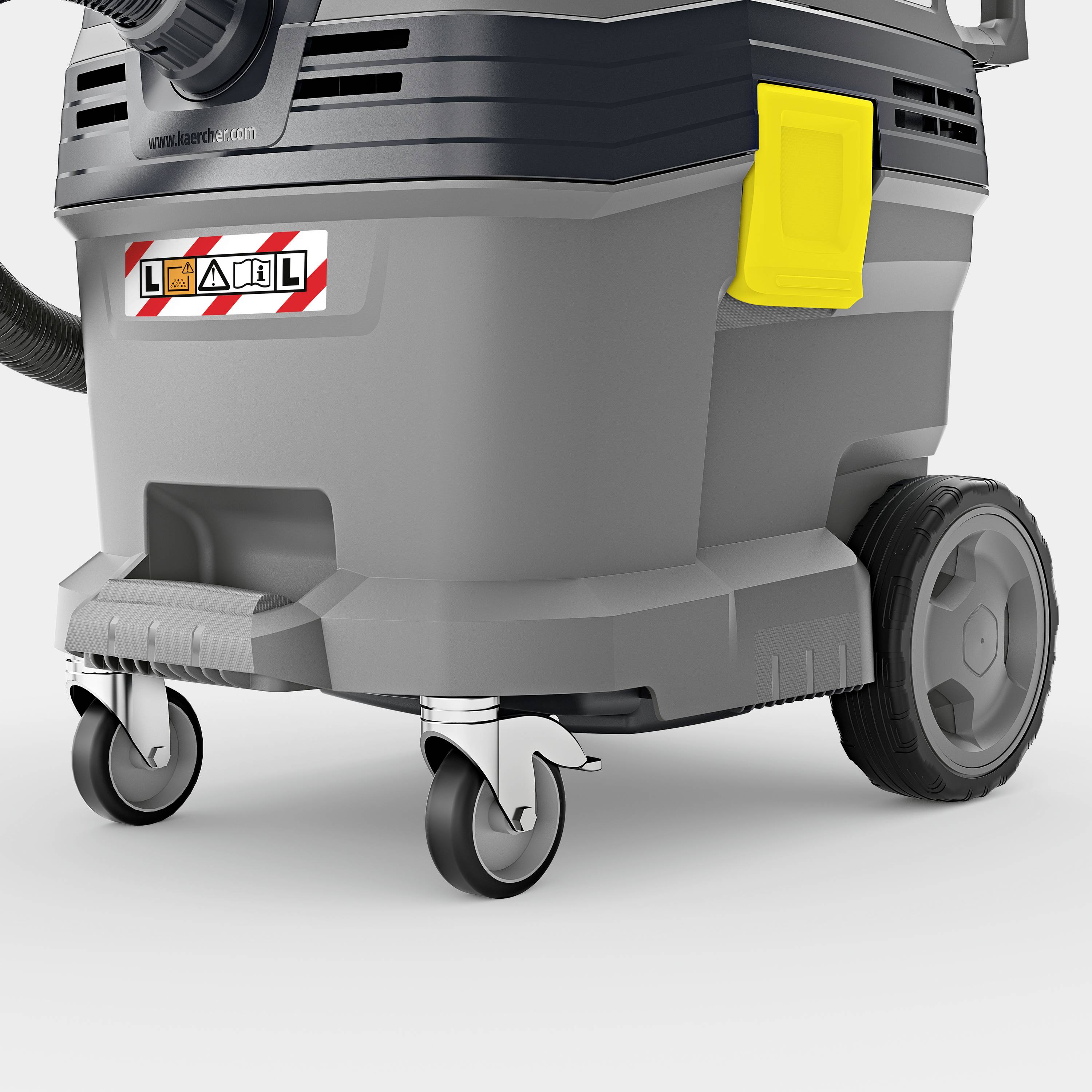 Průmyslový vysavač s kolečky, připojením hadice a žlutou rukojetí na straně. Vhodný pro komerční úklidové práce.