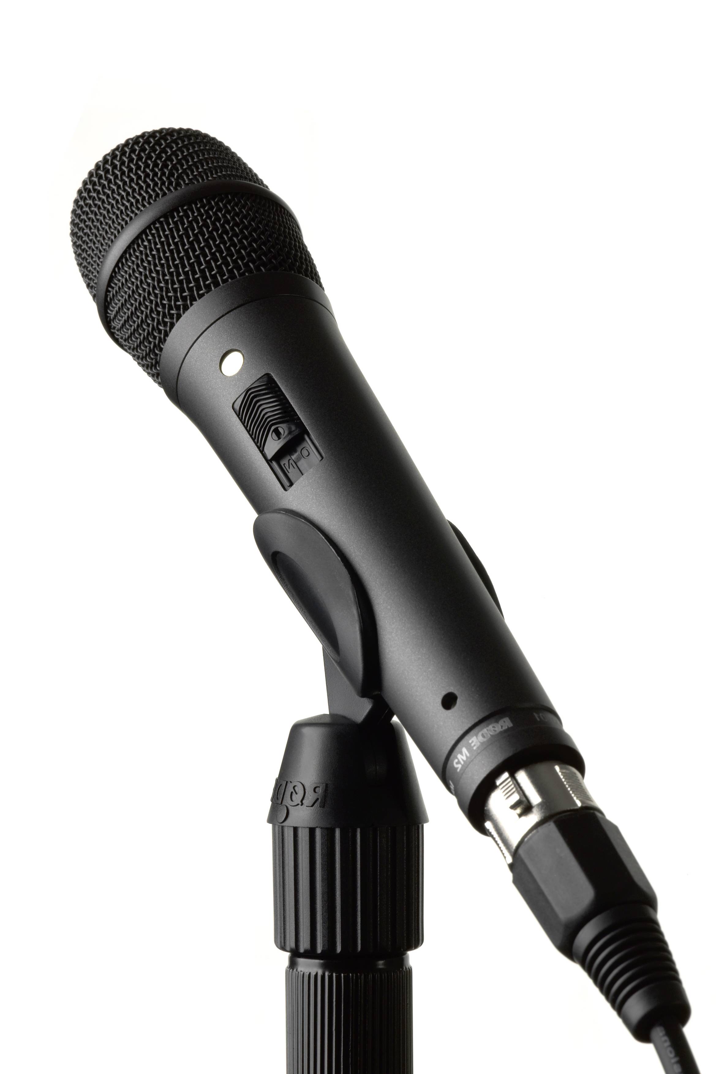 Černý mikrofon na stojanu, mírně nakloněný dopředu, před neutrálním pozadím.
