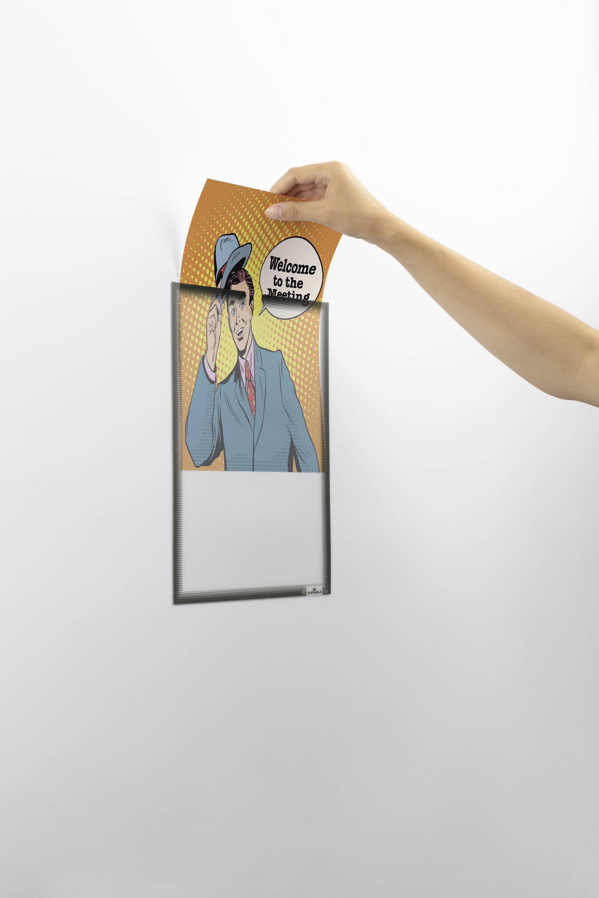 Jedna ruka vkládá kartu s komiksovou postavou do nástěnného držáku. Na kartě je napsáno 'Vítej v revoluci'.