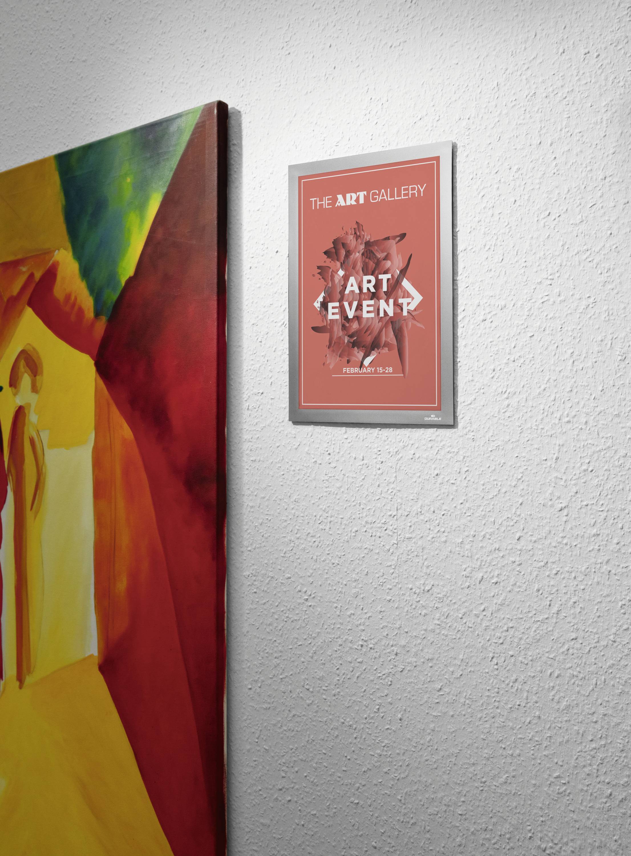 Plakát na zdi s nápisem 'Umělecká galerie - Umělecká akce'. Vedle plakátu je vidět barevný obraz.