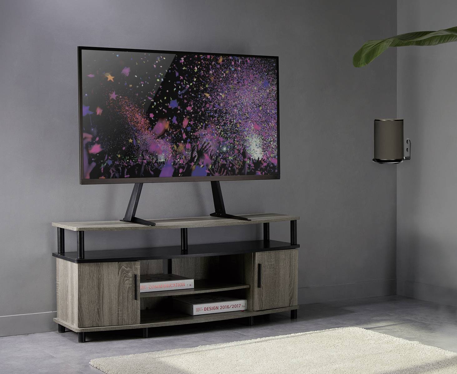 Plochý LED televizi zobrazuje barevný ohňostroj. Stojí na moderní dřevěné TV skříňce v minimalisticky zařízeném prostoru.