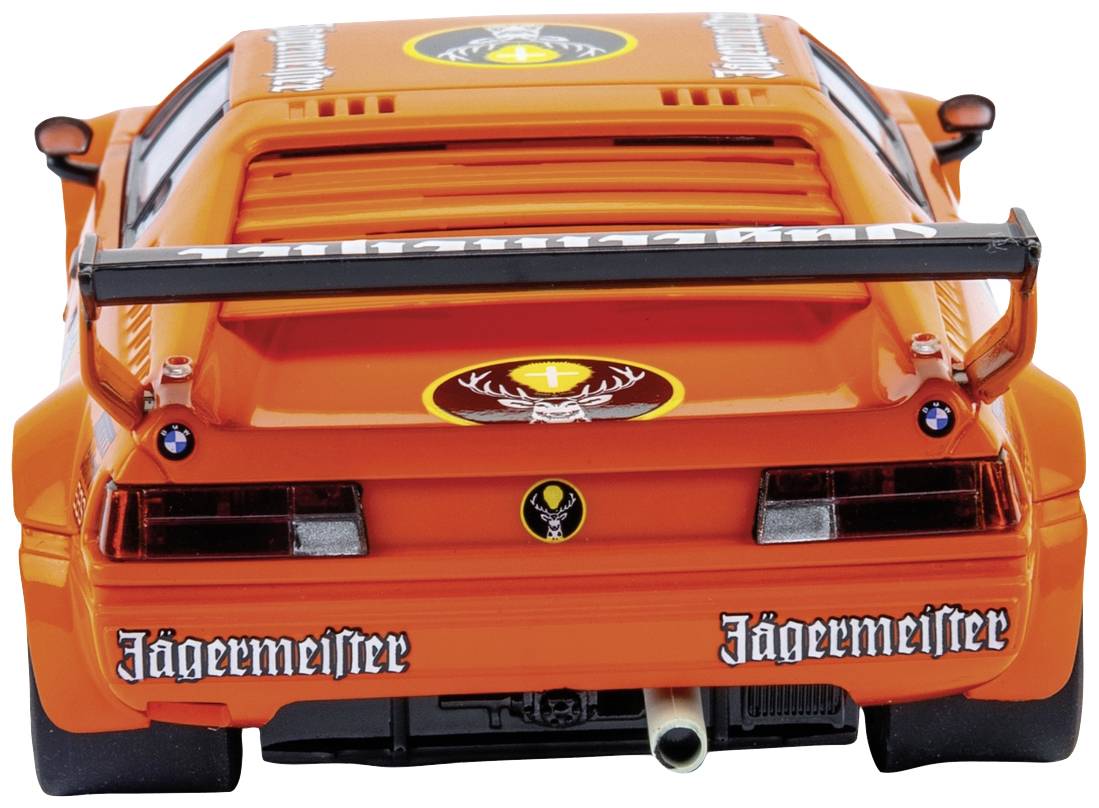 Oranžové sportovní auto s logem Jägermeister je vidět zezadu, přičemž zadní křídlo a výfuk jsou dobře patrné.