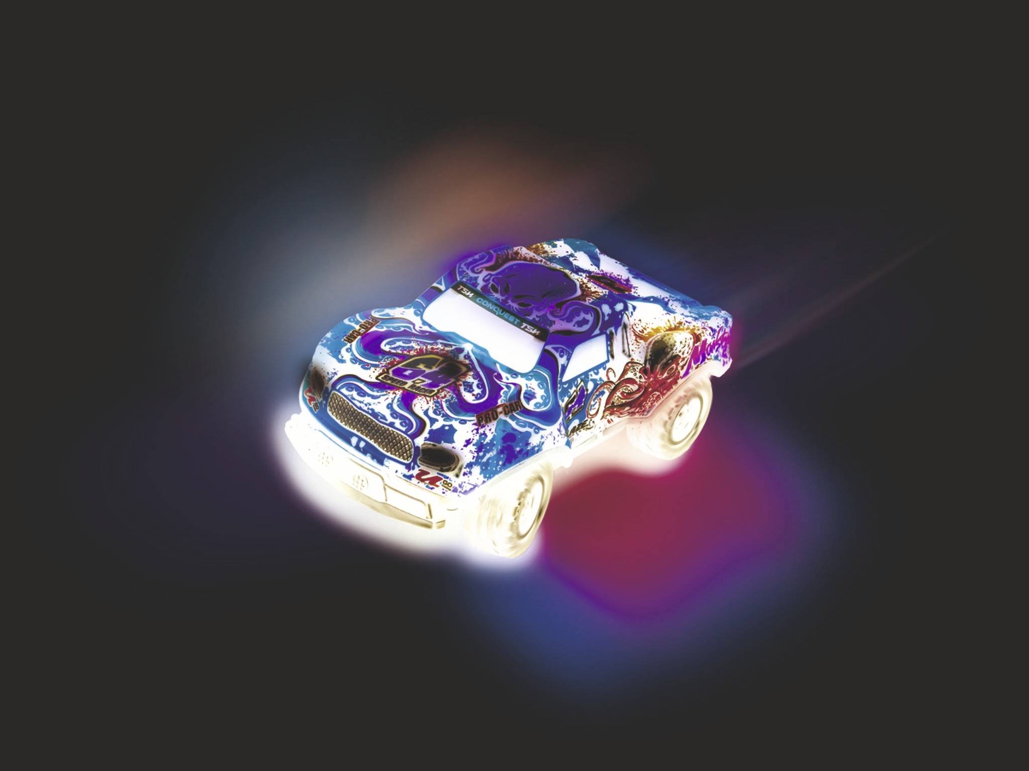 Zářící hračkářské auto s barevným, psychedelickým vzorem jede doprava přes tmavé pozadí. Světla vytvářejí záři.