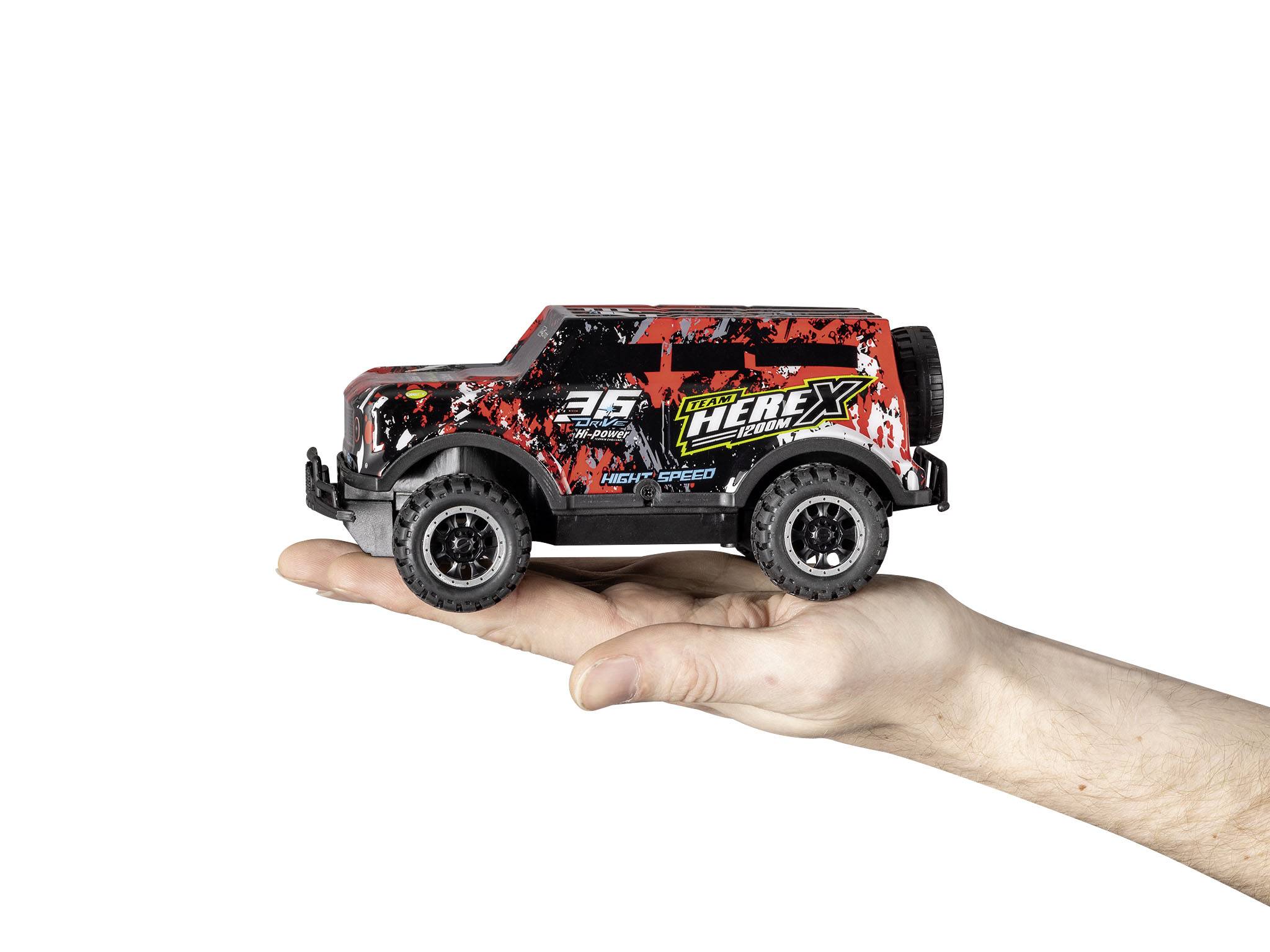 Ruka drží modelové auto ve stylu terénního vozu s nápadným červeno-černým designem a číslem 36 na karoserii.