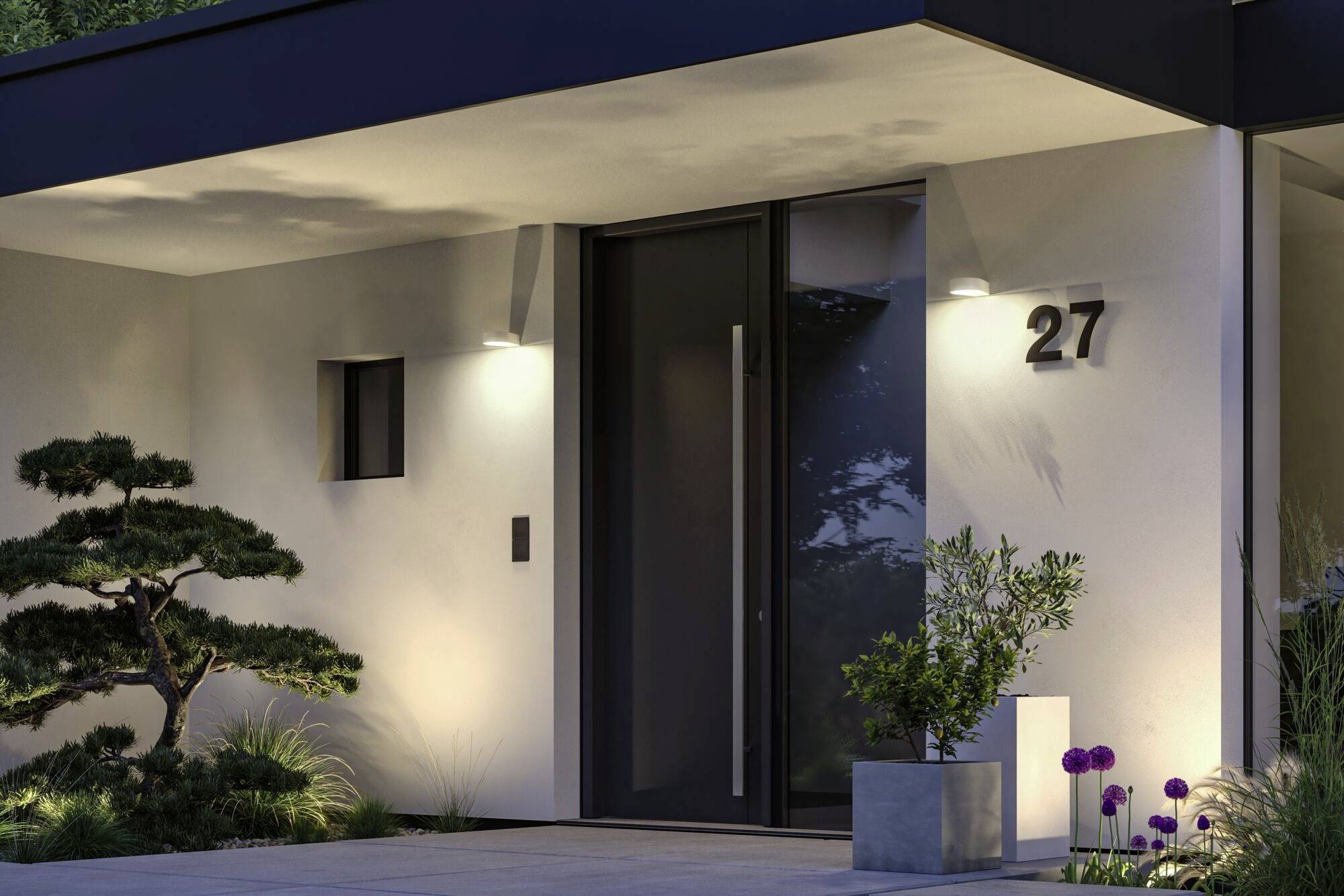 Moderní fasáda domu v noci, osvětlený vstup se skleněnými dveřmi a číslem '27', obklopený rostlinami a minimalistickým designem.