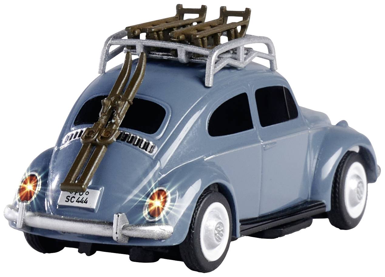 Modré hračkové auto ve stylu klasického VW Brouka, s lyžemi na střešním nosiči. Zadní světla svítí.