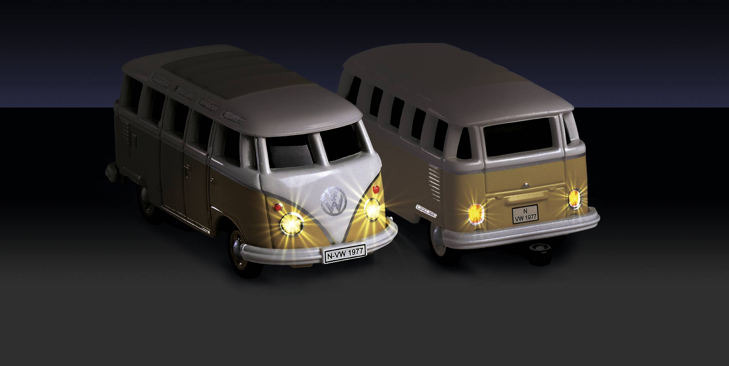 Dva modelové vozy VW autobusu ve zlaté a stříbrné barvě. Oba jsou diagonálně umístěny a ukazují přední a zadní pohled.