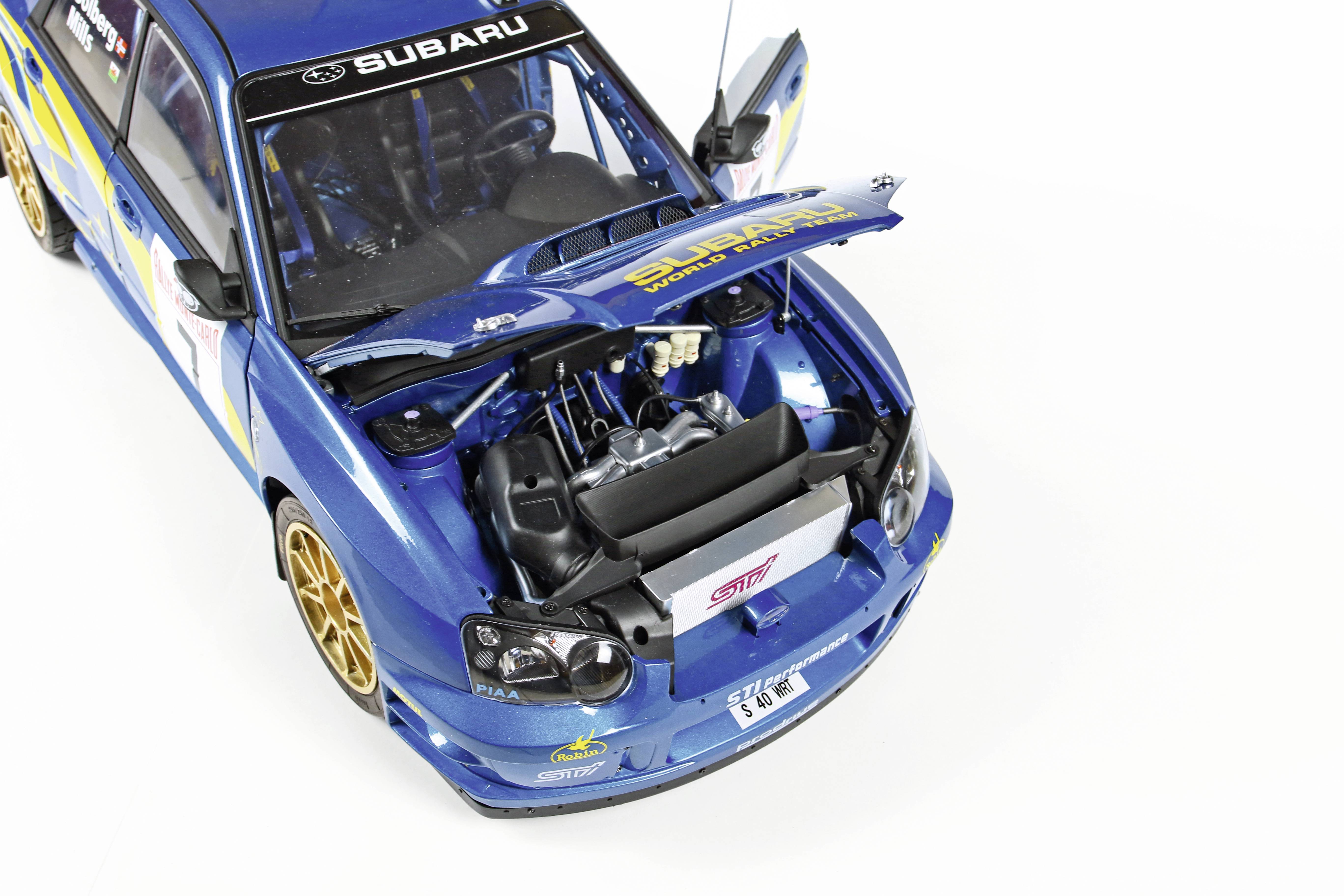Modré hračkové auto s otevřeným motorovým prostorem. Samolepky na kapotě. Ukazuje detaily rallye modelu na bílém pozadí.