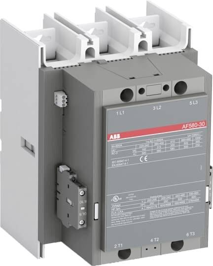 Na obrázku je elektrický stykač s modelovým číslem AF580-30. Vlevo je umístěn doplňkový modul pro optimalizaci funkce.