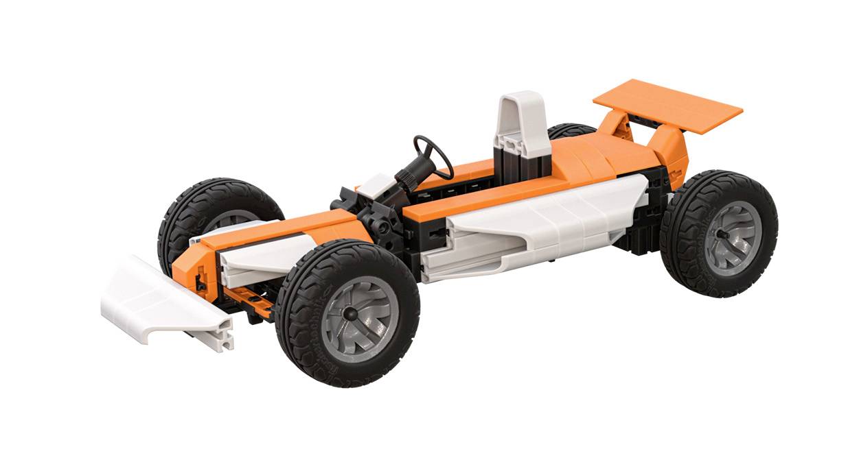 Oranžovo-bílé modelové auto s designem závodního vozu, složené z konstrukčních dílků. Má černé pneumatiky a zadní křídlo.