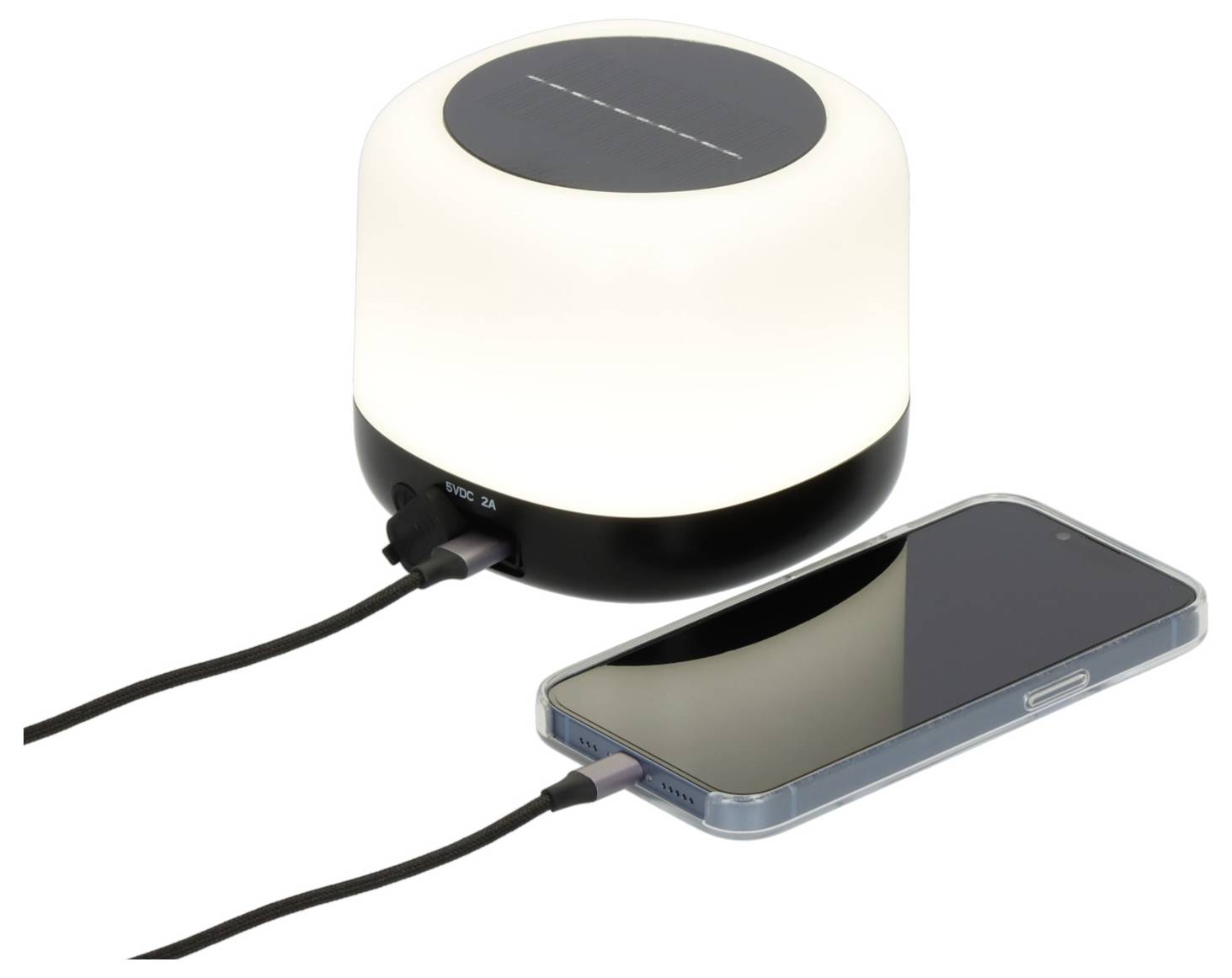 Bezdrátová nabíjecí lampa svítící bíle při nabíjení chytrého telefonu přes kabel na bílém pozadí.