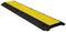Zpomalovací práh na silnici, žluto-černý, používaný ke zklidnění dopravy a jako výstražný signál pro řidiče.