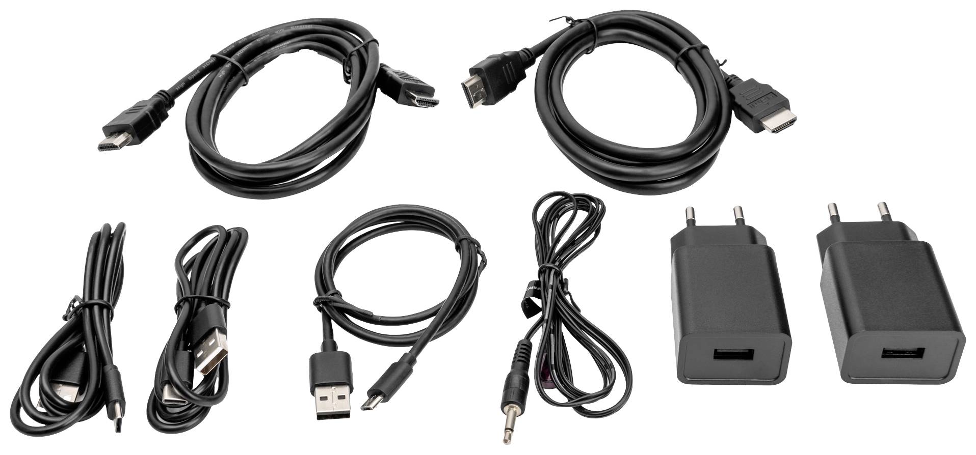 Vedle sebe leží různé kabely a adaptéry: USB kabel, HDMI kabel, audio kabel a dva černé síťové adaptéry.