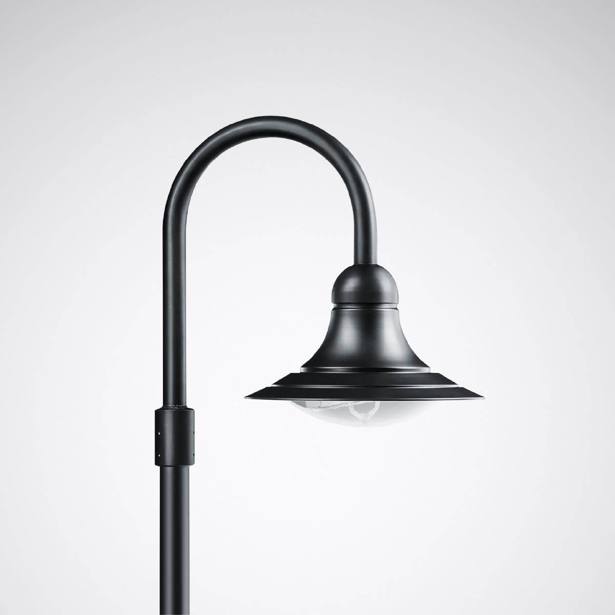 Černá pouliční lampa s ohnutým sloupem a kulatým stínidlem před šedým pozadím.