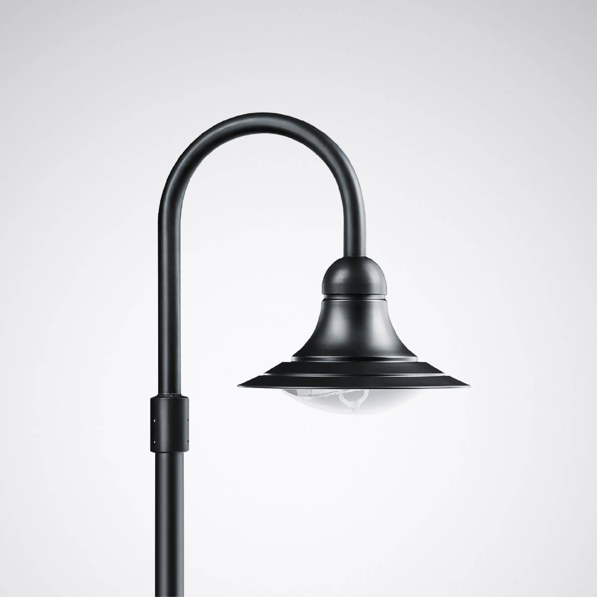 Černá, zakřivená pouliční lampa s klasickým designem před světle šedým pozadím. Má kulatý stínidlo.