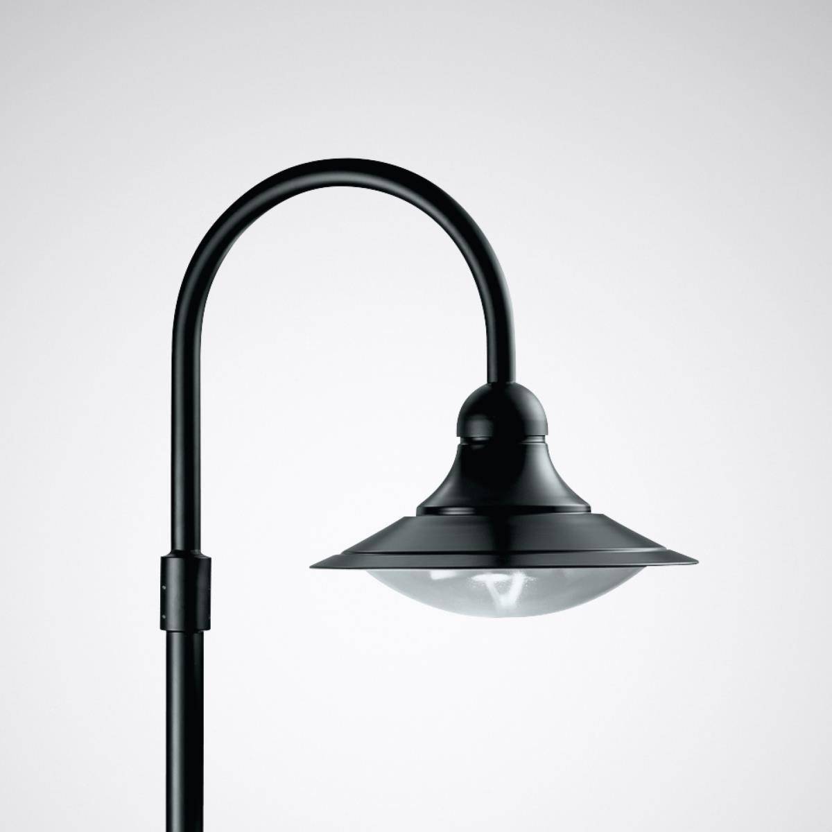 Černá pouliční lampa s ohnutým sloupem a kulatým stínidlem před šedým pozadím.