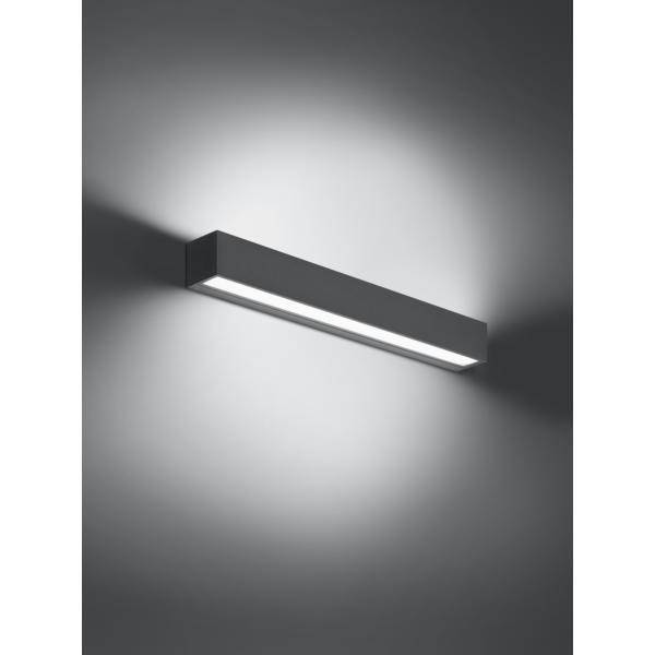 Obdélníková nástěnná lampa z kovu svítí v jednoduchém, moderním designu měkkým světlem.