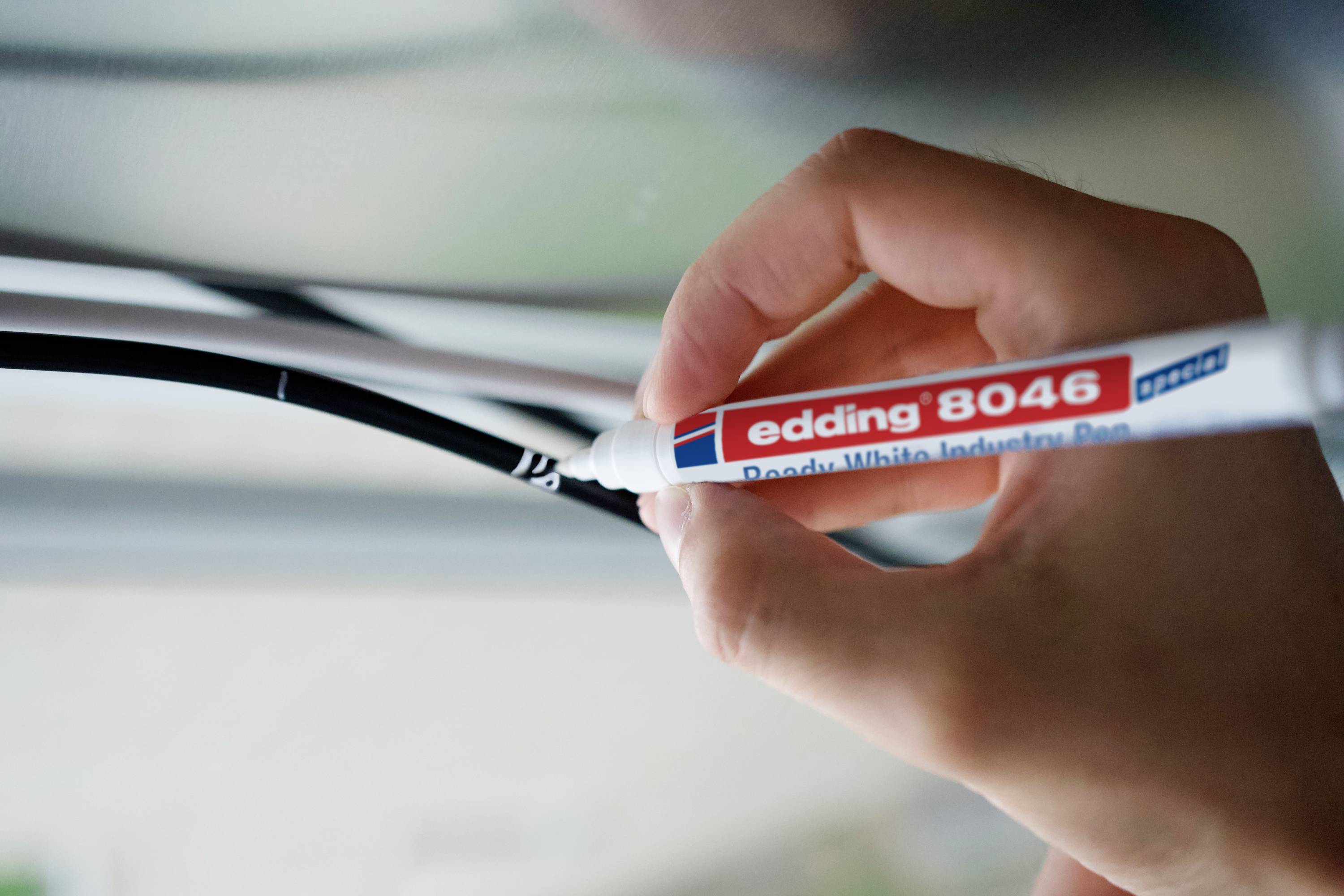 Ruka drží bílý fix a označuje černý kabel. Fix je popsán jako "edding 8046".