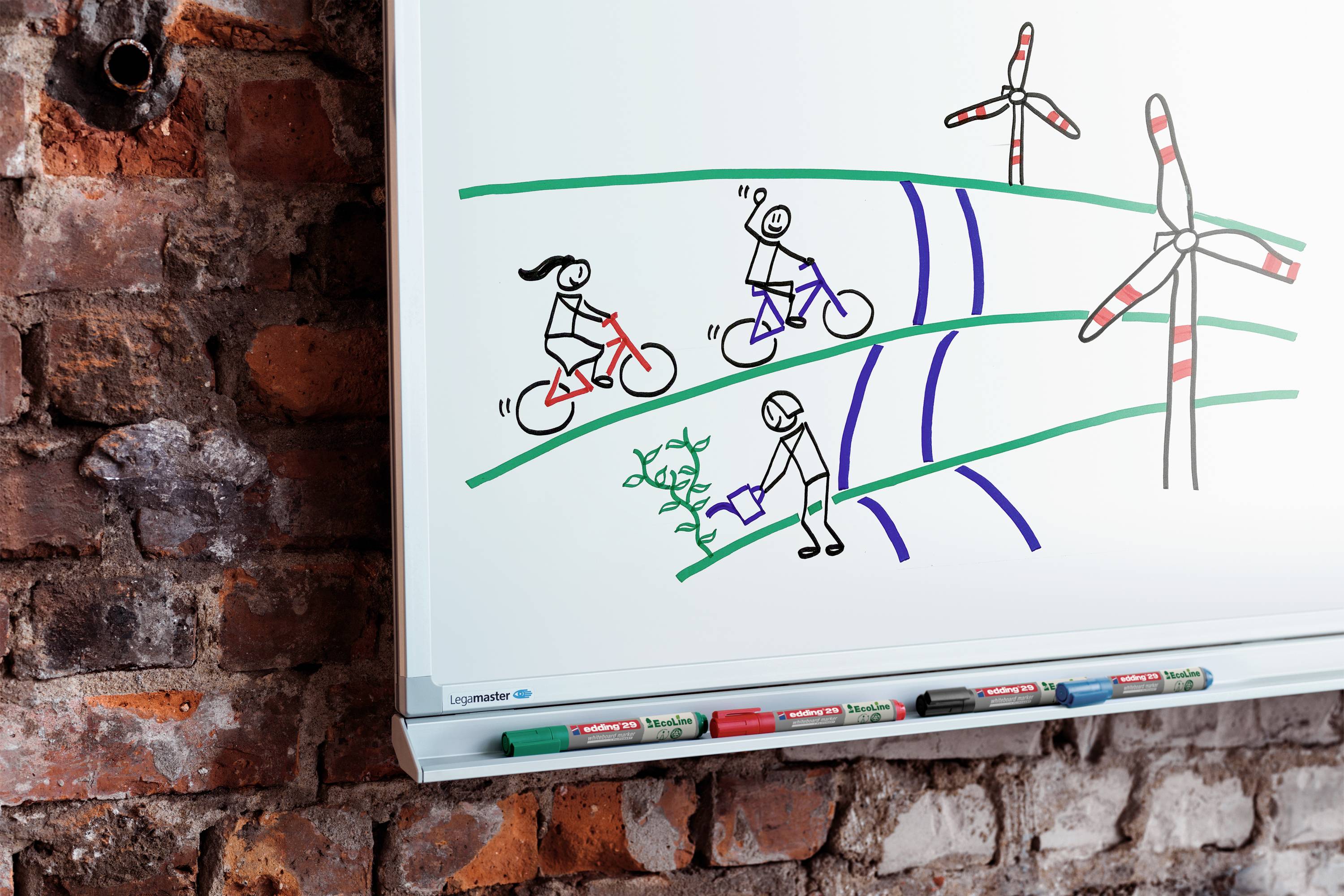 Bílá tabule zobrazuje kresbu dvou cyklistů a osoby zalévající rostliny před větrnými turbínami.