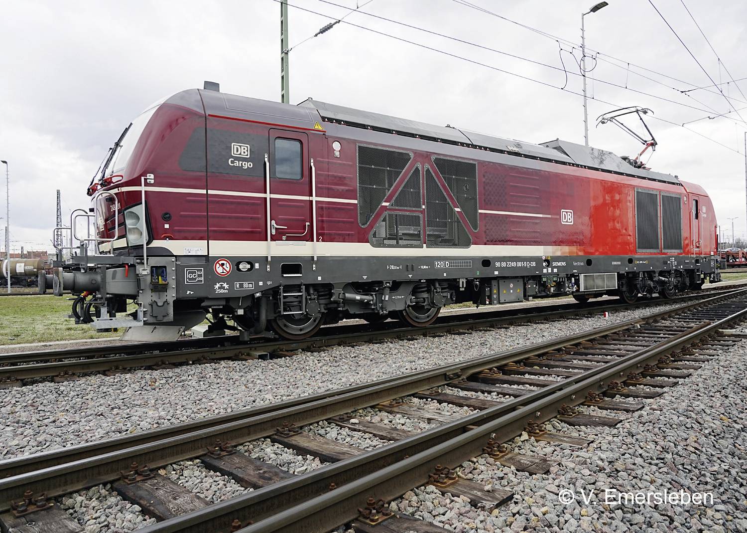 Červená lokomotiva DB Cargo stojí na koleji. Vykazuje moderní konstrukční provedení a je připravena k přepravě nákladu.