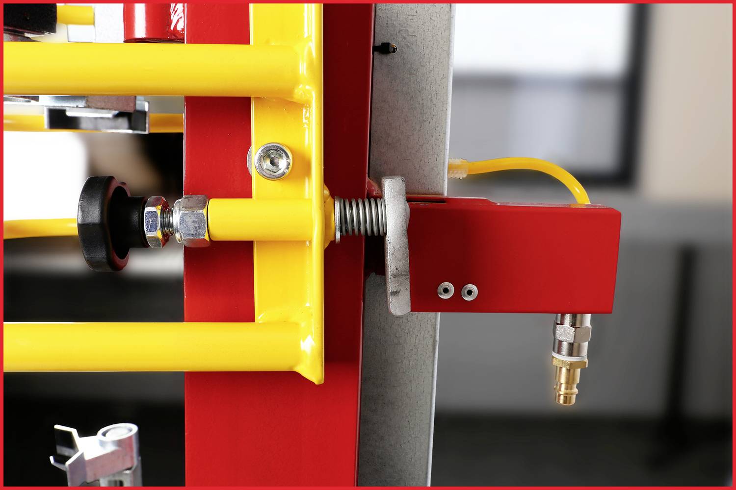 Detailní snímek ukazuje červeno-žlutý bezpečnostní ventil nebo uzavírací mechanismus připevněný k kovovému rámu.