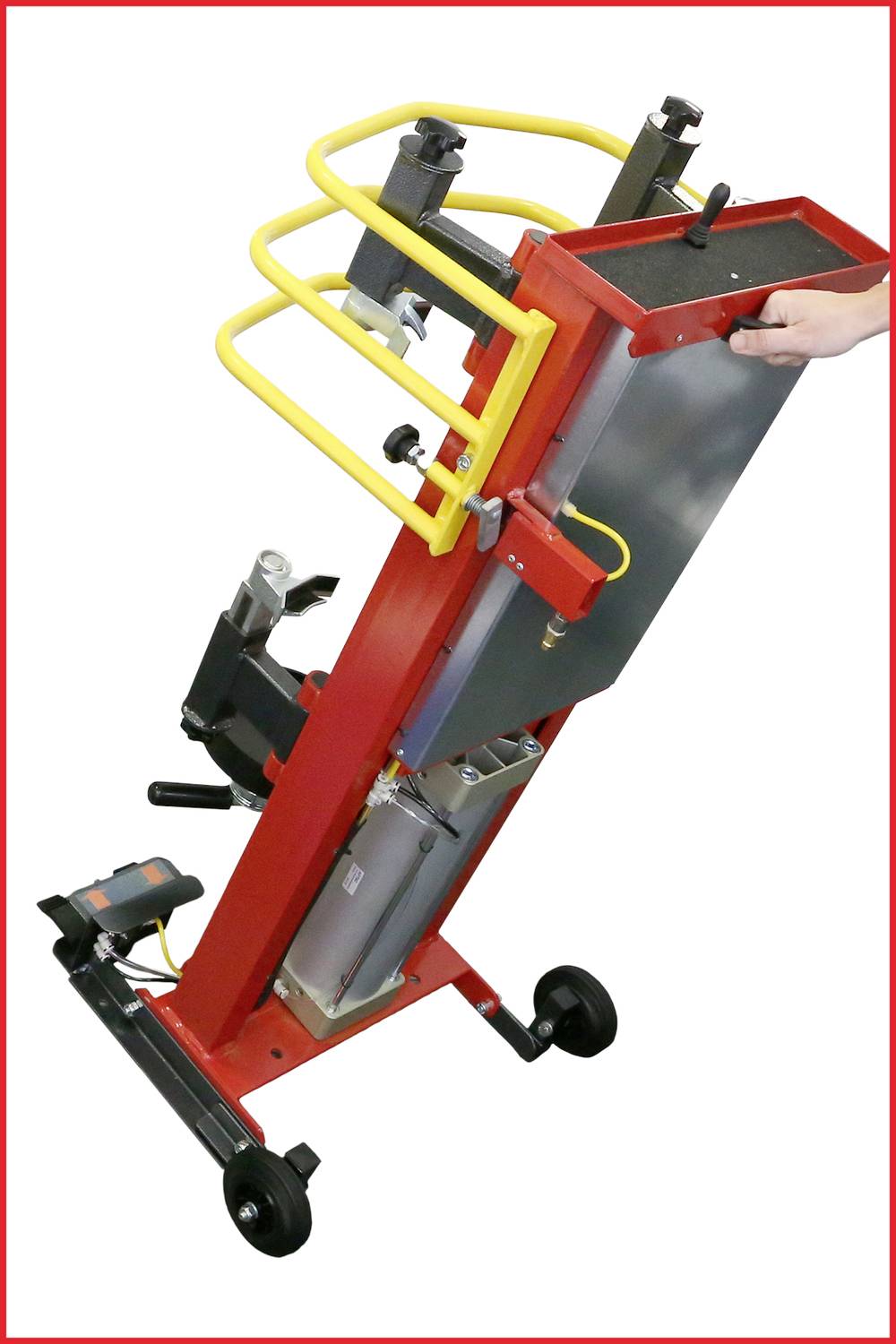Červeno-žluté mechanické zařízení s kolečky, úchopovou rukojetí a zvedací/podpěrnou funkcí. Jedna ruka obsluhuje kovovou desku.