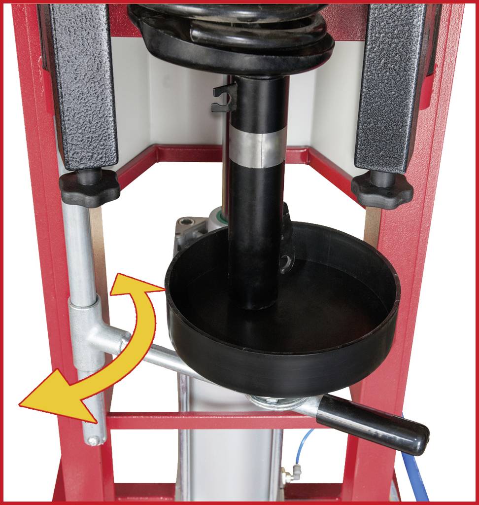 Hydraulický lis s černou deskou a pákou na pravé straně. Šipka ukazuje pohyb páky.