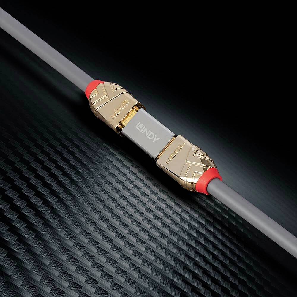 Vysoce kvalitní, pozlacený USB kabel ležící na strukturované černé podložce; zdůrazňuje technologicky orientovanou estetiku.
