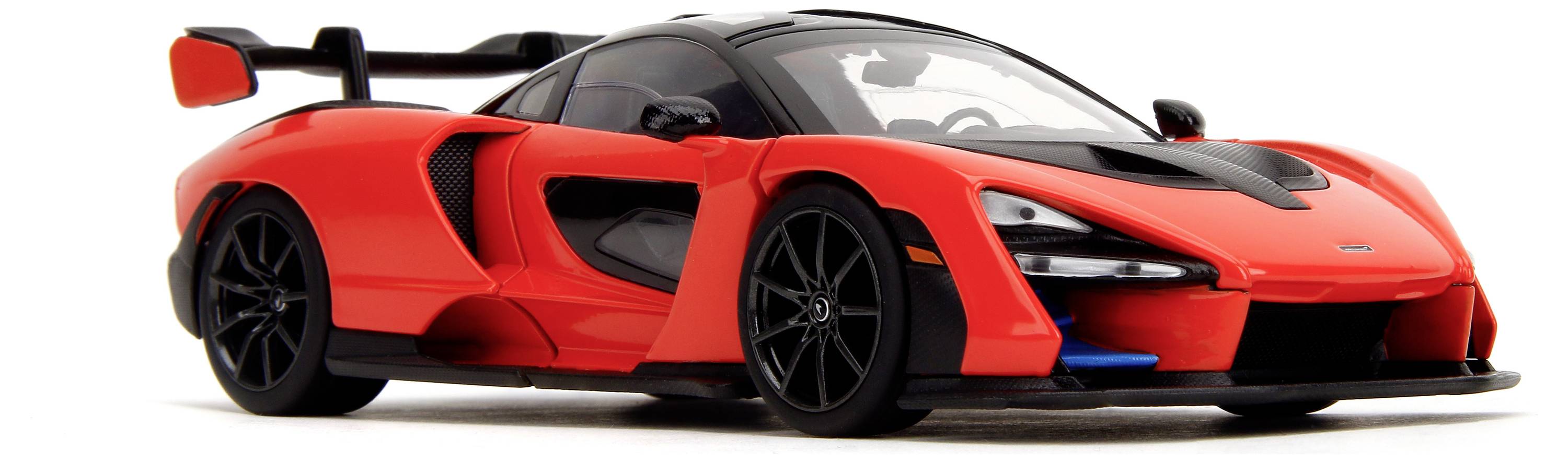 Červený sportovní vůz s černou střechou a velkým zadním křídlem, zaparkovaný na bílém povrchu. Moderní, aerodynamický tvar.