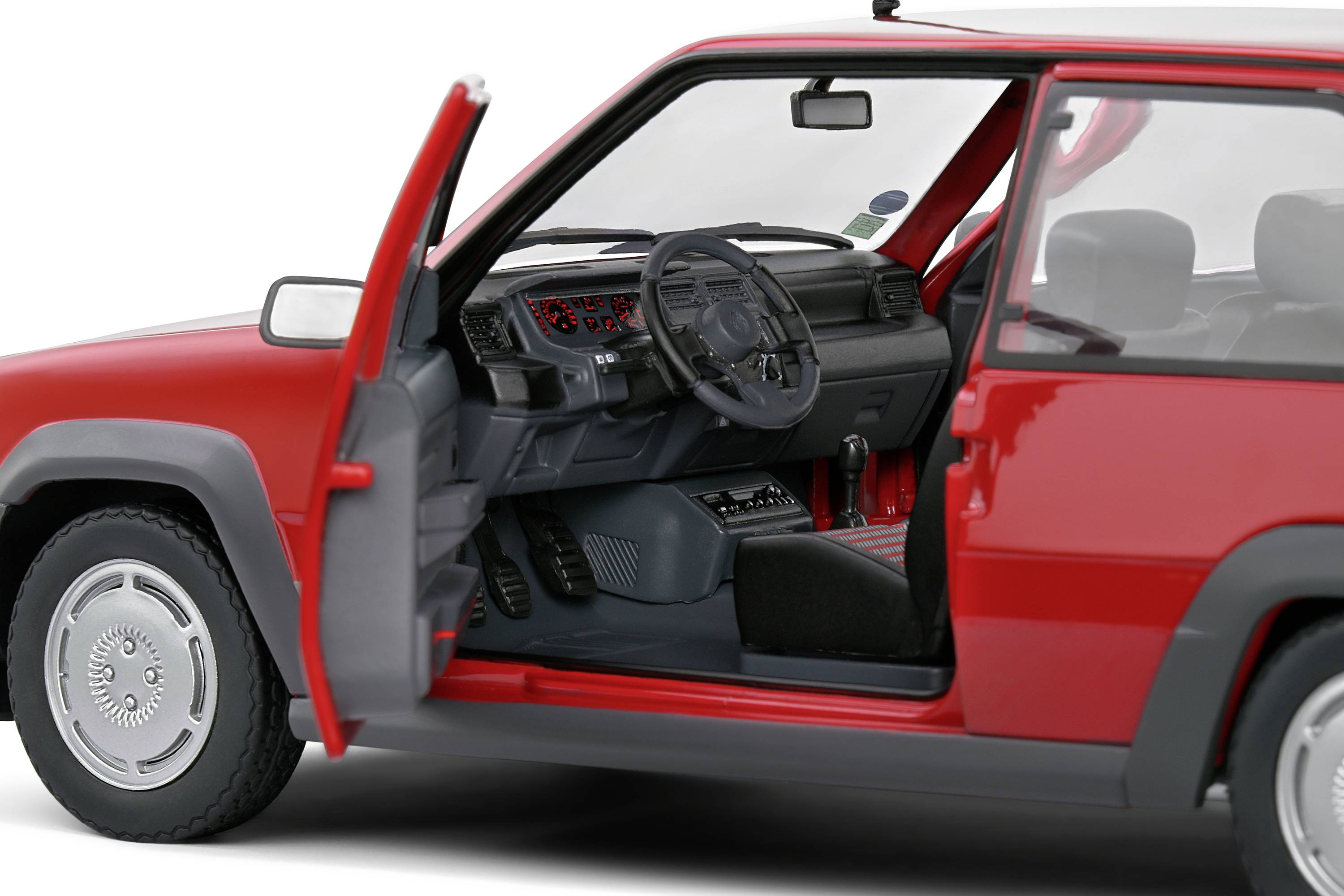 Červené auto s otevřenými řidičovými dveřmi odhaluje interiér vozidla s volantem a předním sedadlem. Důraz je kladen na vnitřní prostor automobilu.