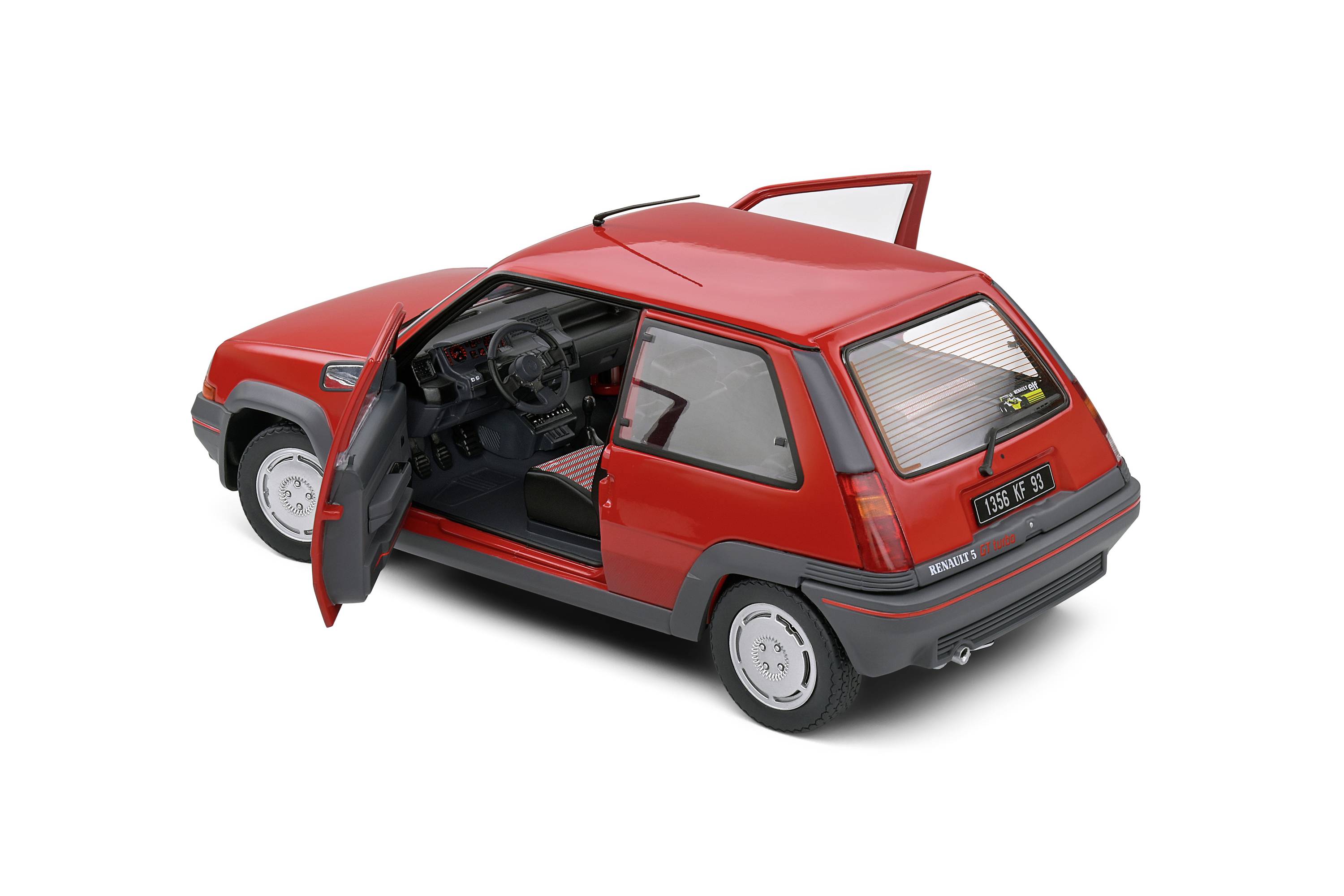 Červené auto se otevřenými dveřmi, focené z mírně zadního pohledu. Ukazuje interiér a detaily vozidla.