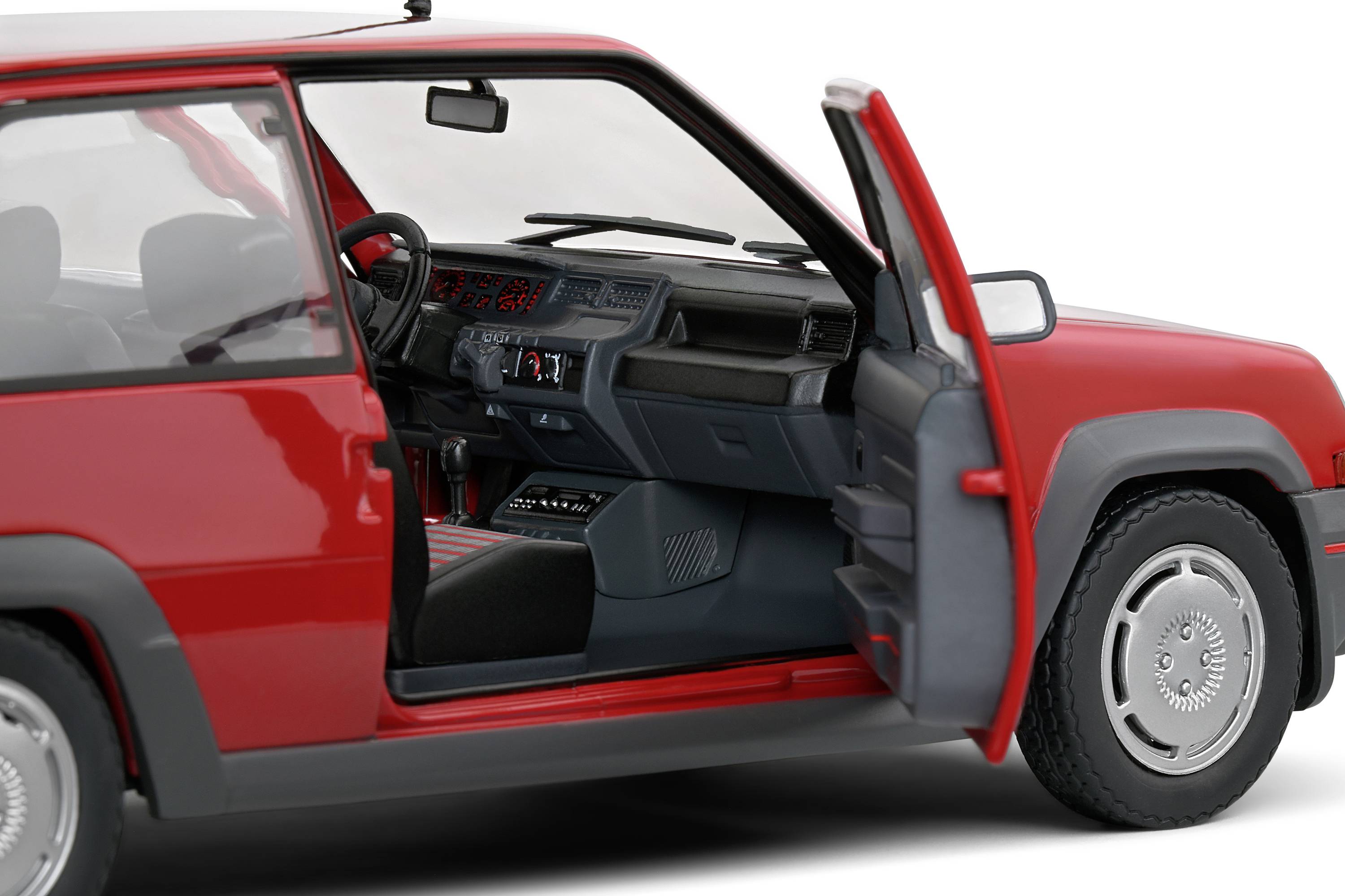 Červené auto s otevřenými řidičovými dveřmi odhaluje interiér se zaměřením na volant a přístrojovou desku.