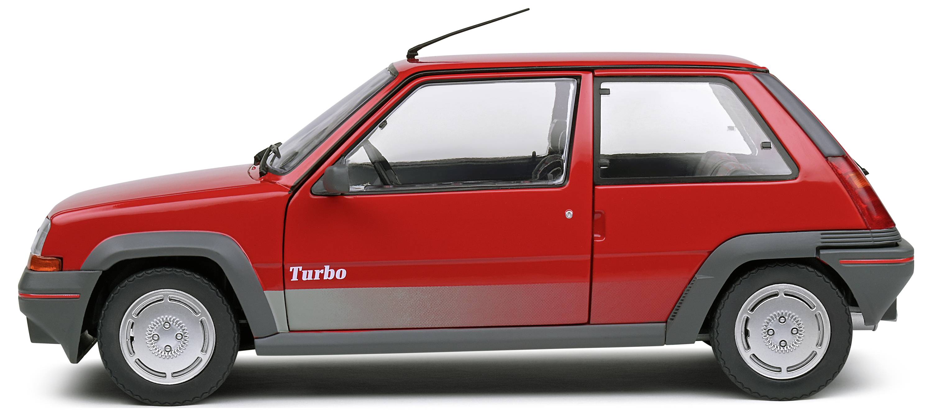 Červený malý vůz s nápisem 'Turbo' na boku, pohled zleva. Kompaktní, vhodný pro jízdu ve městě, vykazuje sportovní design.