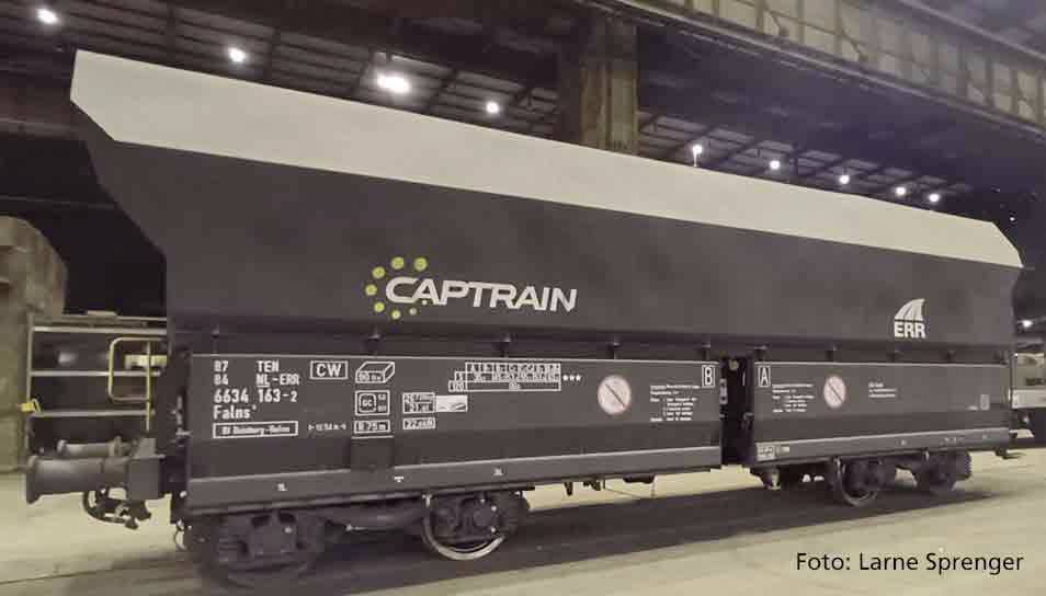Nákladní vůz společnosti Captrain stojí v hale. Vůz je černý s bílým a žlutým označením.