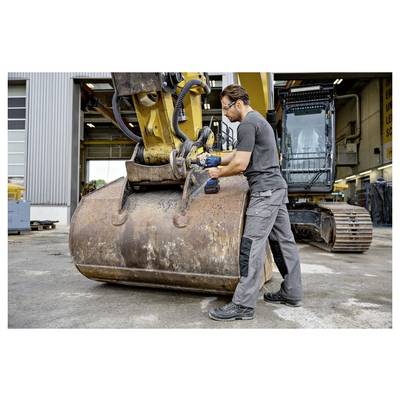 Mechanik používající elektrický nástroj k údržbě kýble velkého bagru v dílně na údržbu.