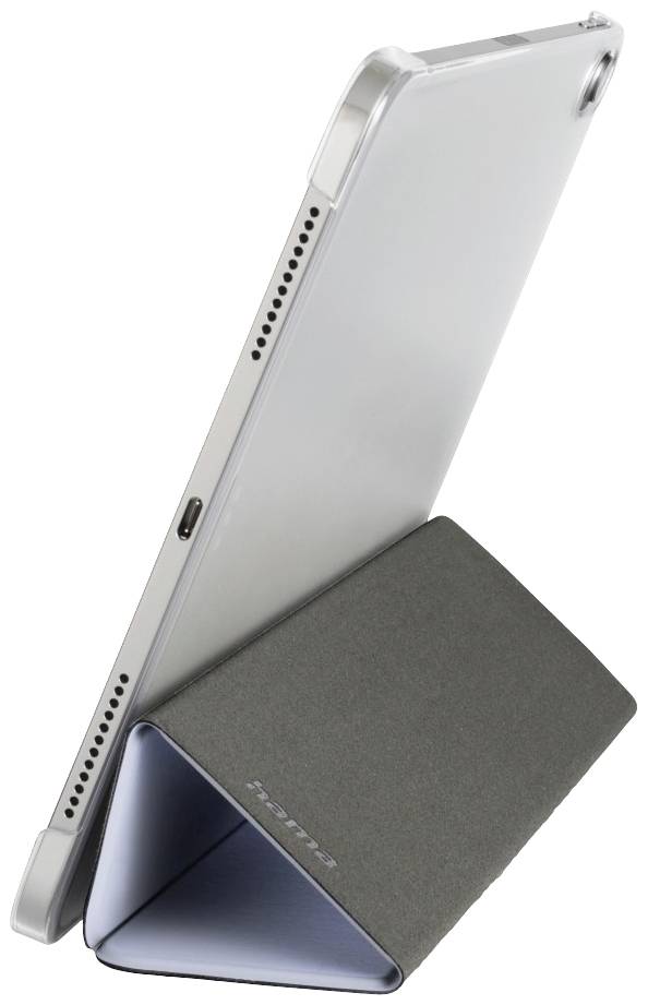 Tablet stojí vzpřímeně v šedém obalu, který slouží jako stativ. Porty a reproduktory jsou viditelné.