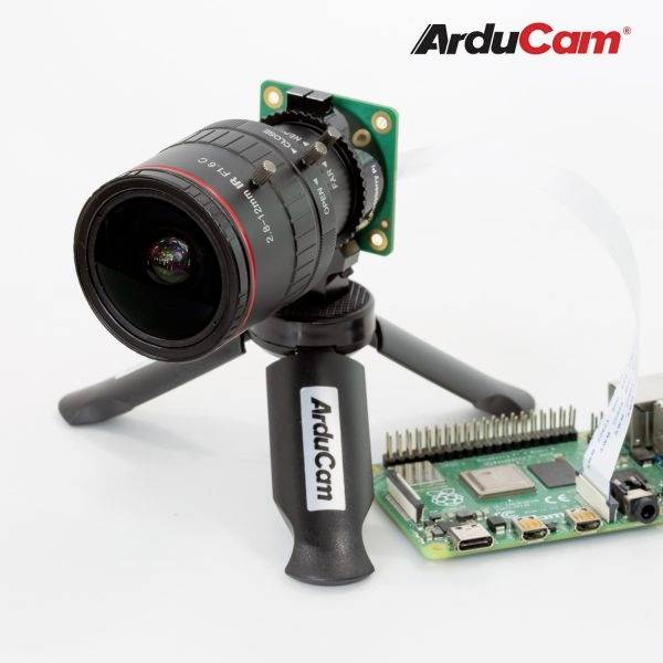 Kamera ArduCam na miniaturním stativu, připojená k Raspberry Pi, na bílém pozadí.