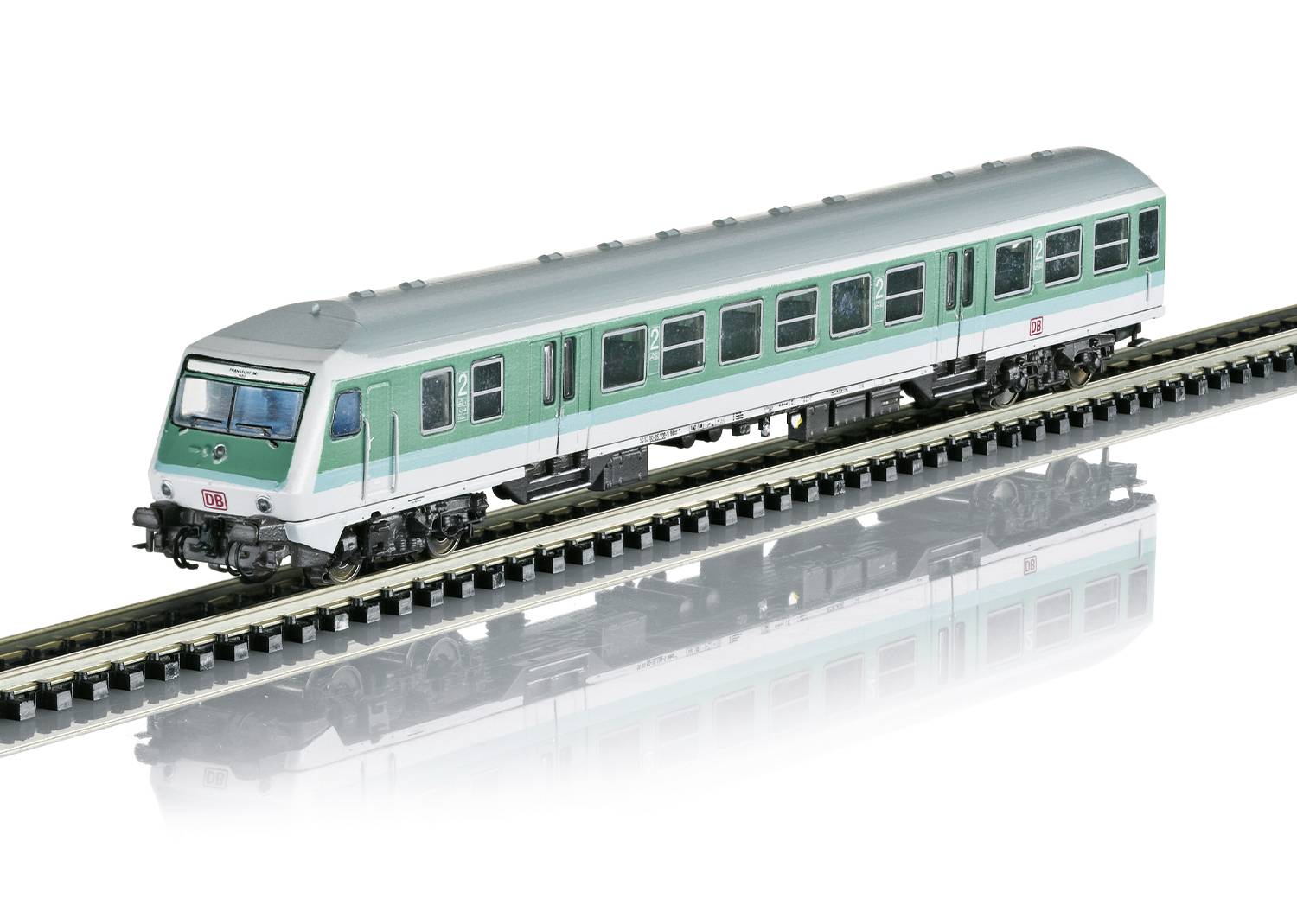 Zelený model vagónu na kolejnici, znázorněný jako hračkářská železnice.