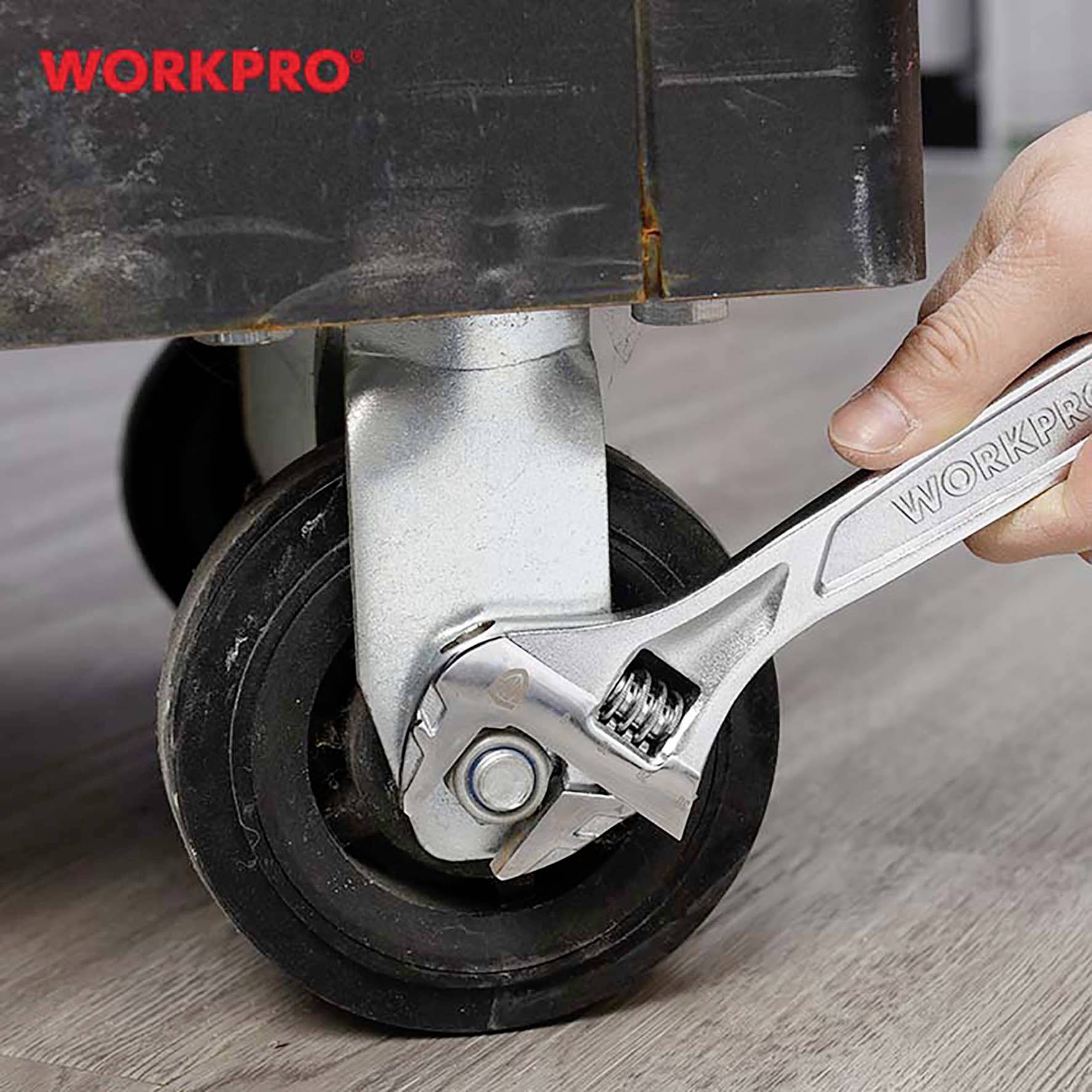 Jedna ruka používá nastavitelný klíč k utažení matice kola na vozíku. Vlevo nahoře je nápis 'WORKPRO'.