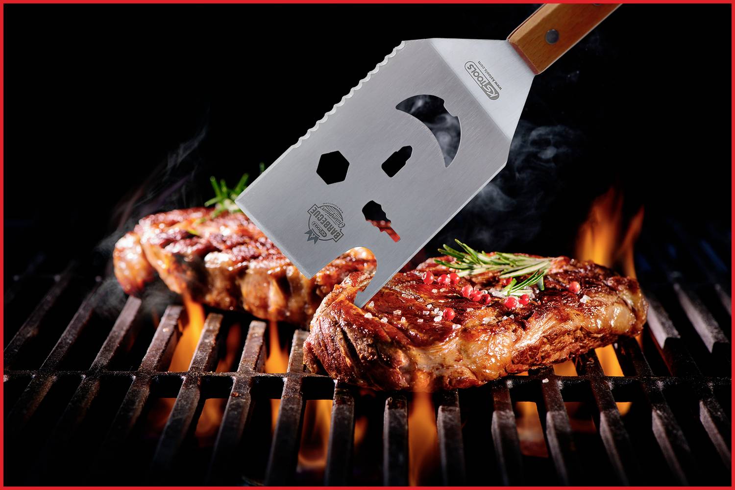 Obracečka zvedá grilované steak s bylinkami z roštu obklopeného plameny.