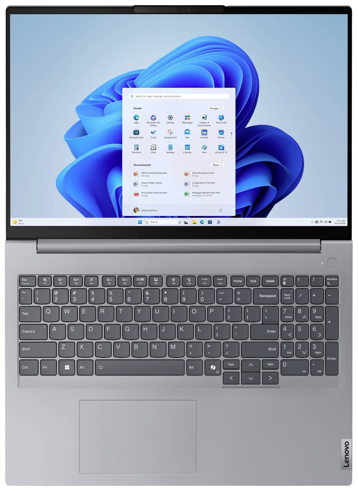 Laptop s otevřeným displejem zobrazuje úvodní obrazovku Windows s dlaždicemi a ikonami. Klávesnice a touchpad jsou viditelné.