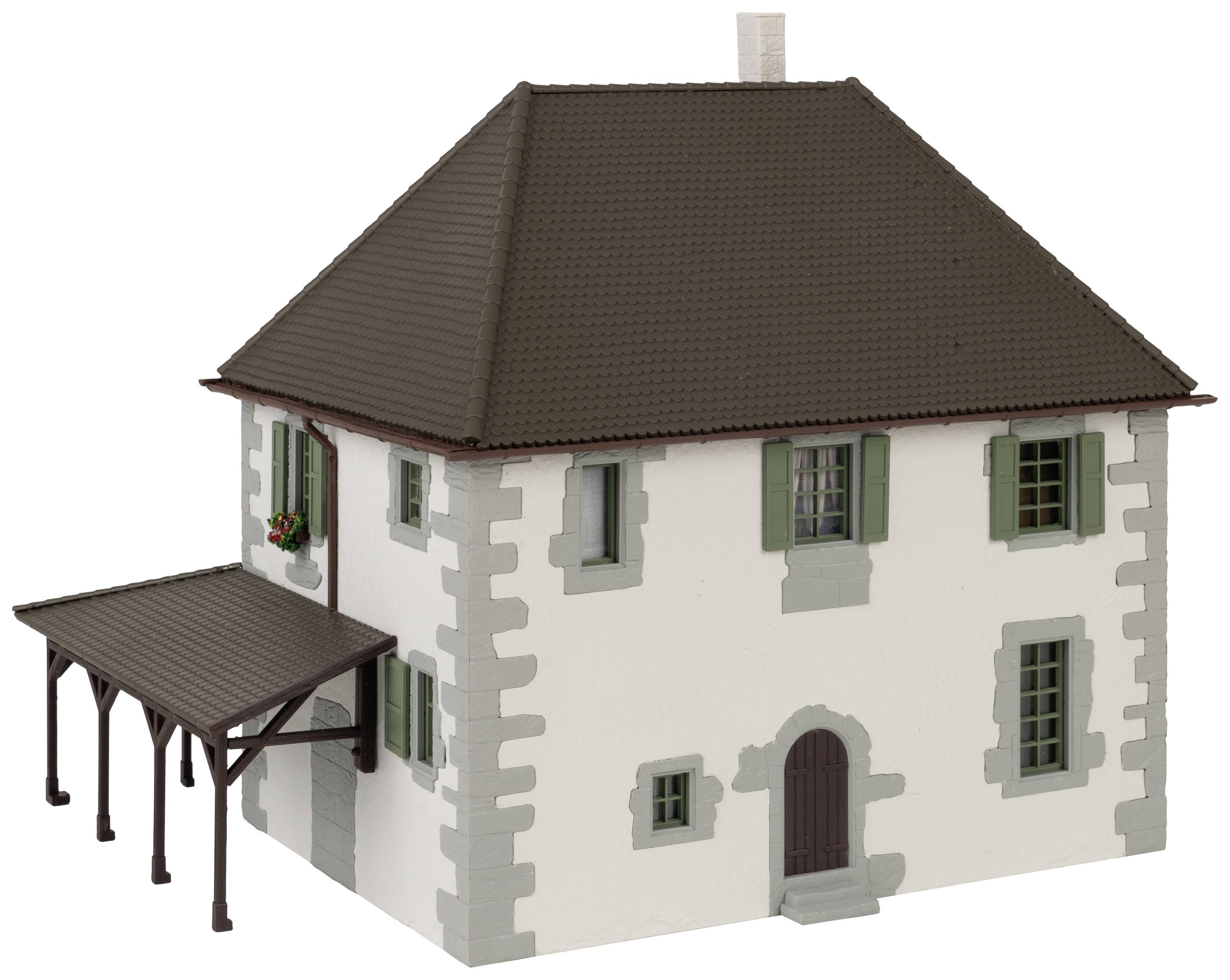 Dvoupatrový modelový dům s hnědou střechou, bílými stěnami a zelenými okenicemi, vedle něhož se nachází zastřešený vchod.