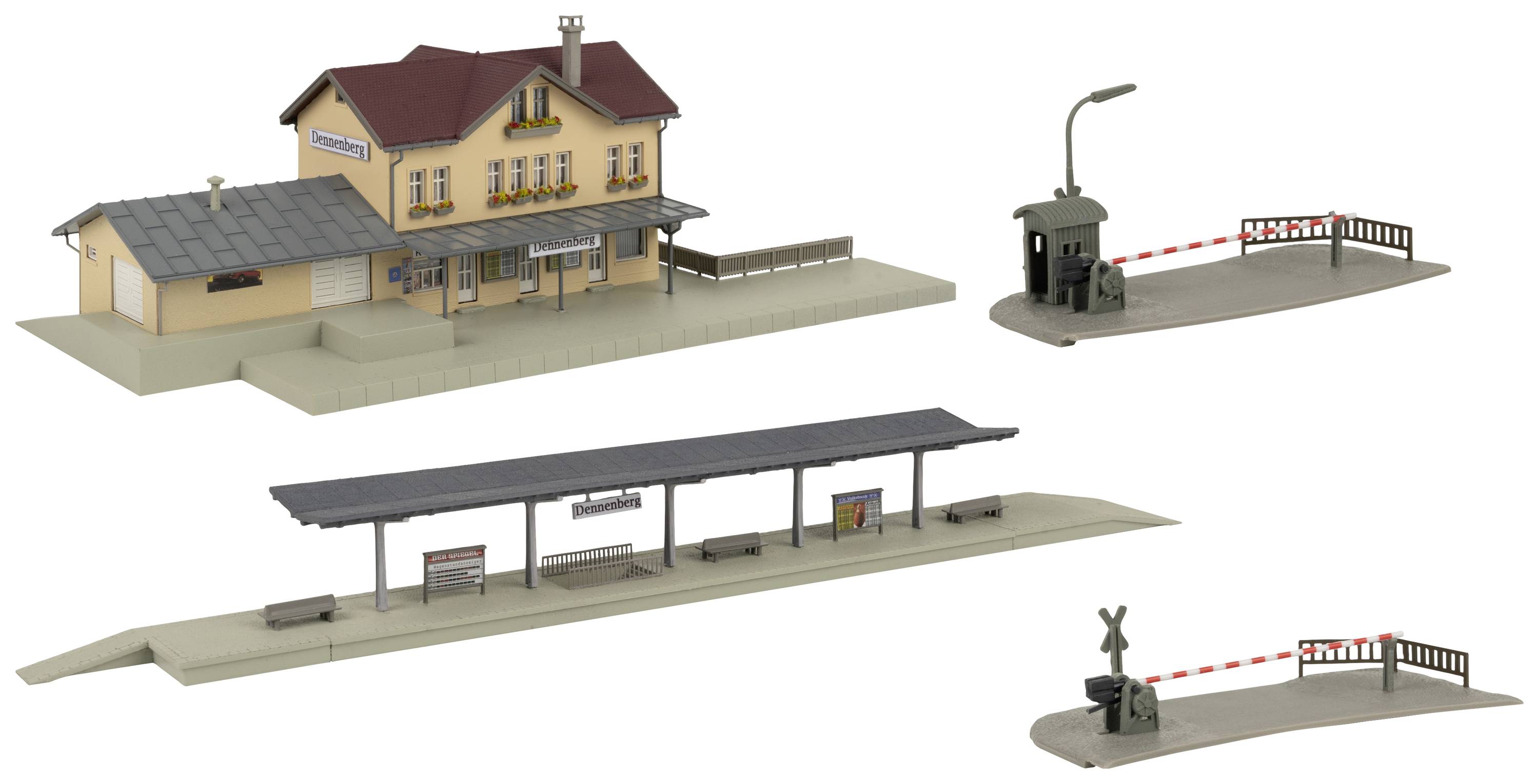 Model malého železničního komplexu s odbavovací budovou, nástupištěm, domkem hradla a závorami.