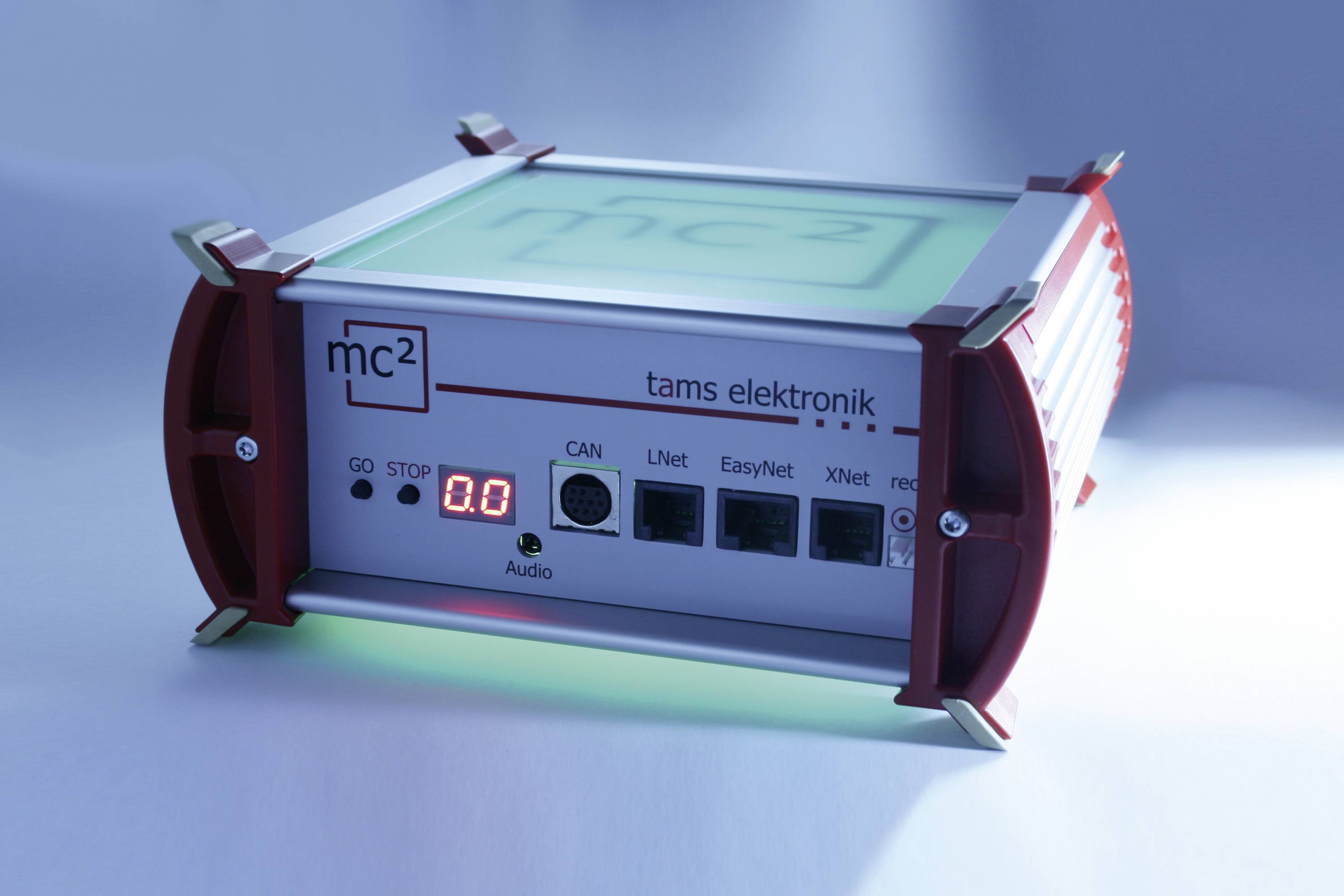 Elektronické zařízení s displejem zobrazuje 'mc²' a 'tams elektronik', má rozhraní pro Audio, CAN, LNet, EasyNet a XNet.