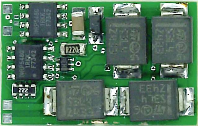 Malá zelená elektronická součástka s několika černými čipy a stříbrnými kontakty na desce plošných spojů.
