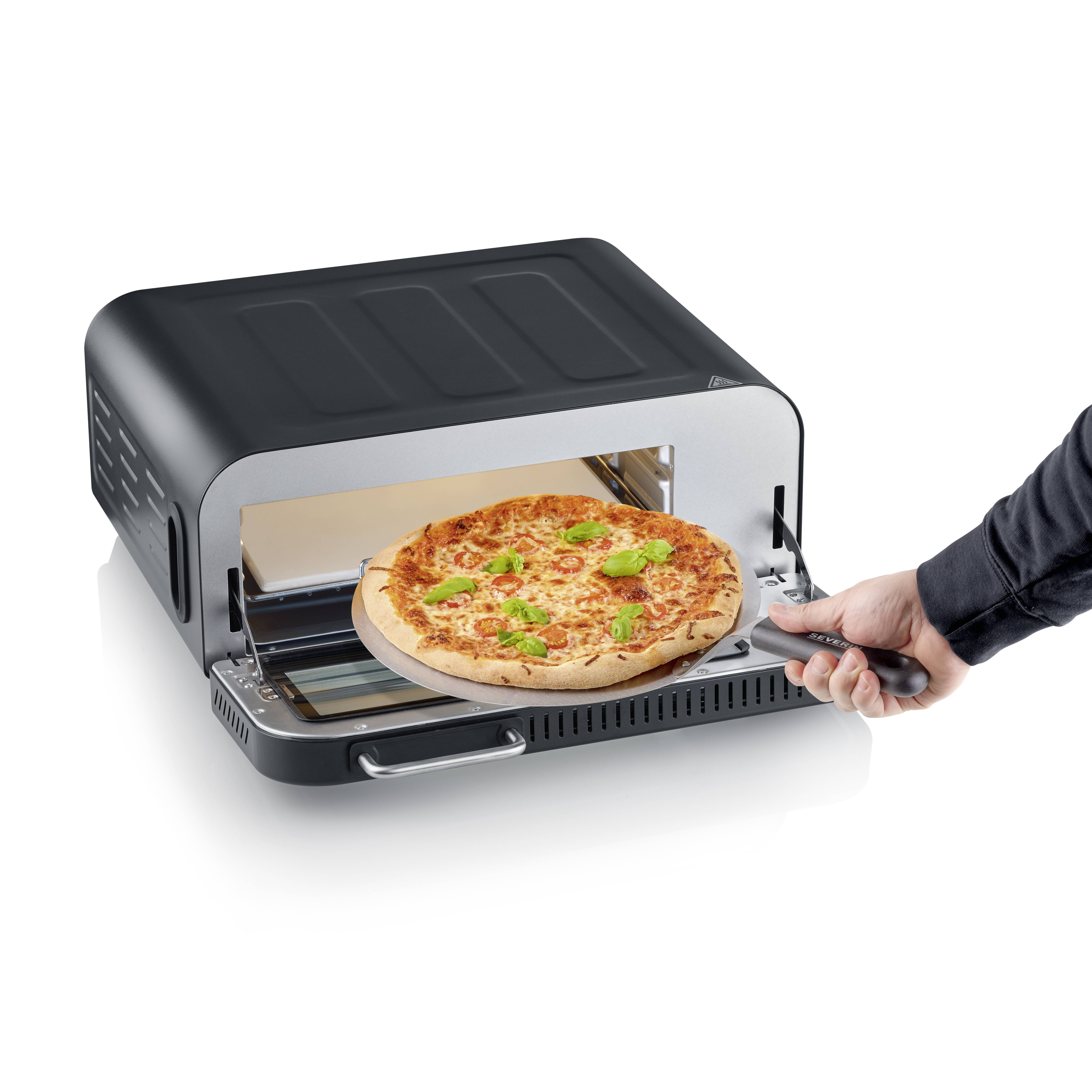 Pec na pizzu s otevřenými dvířky ukazuje čerstvě upečenou pizzu s rozteklým sýrem a zelenými lístky na lopatkách na pizzu.